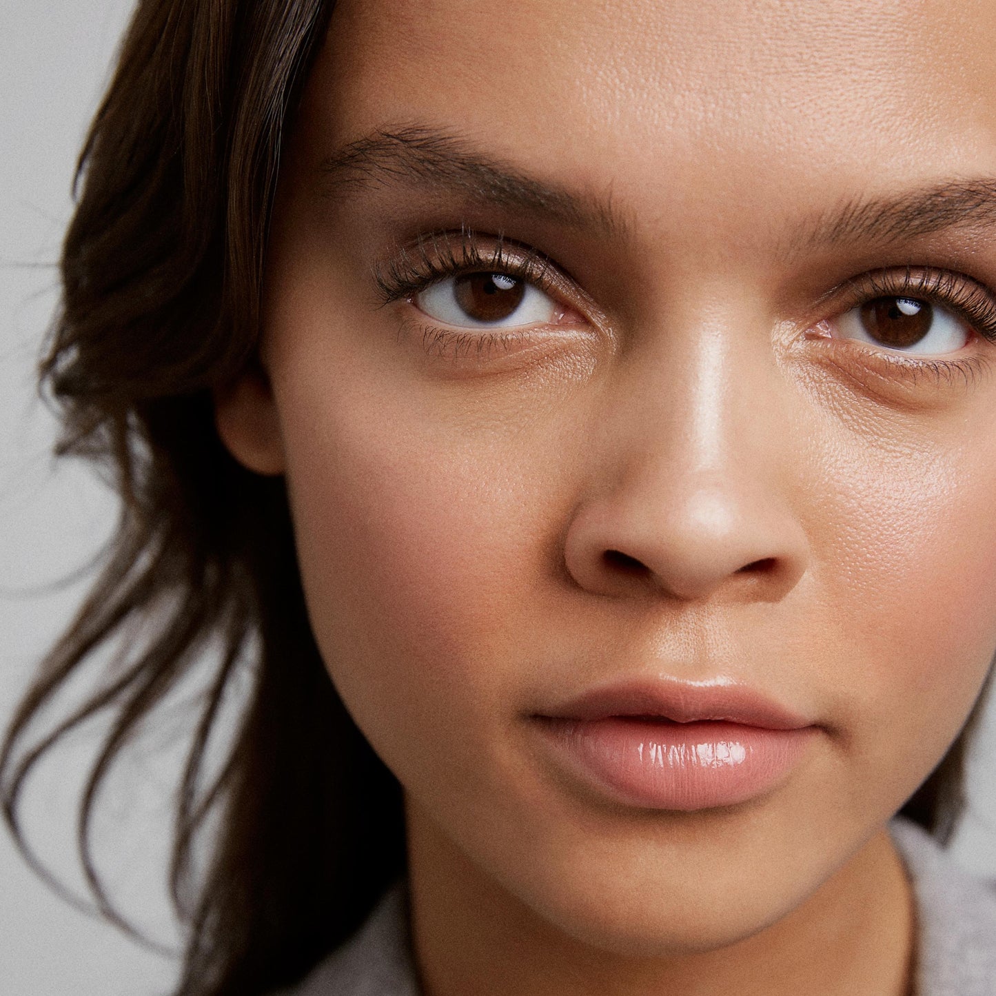 Close up of person’s face with a medium skin tone wearing cream eye shadow