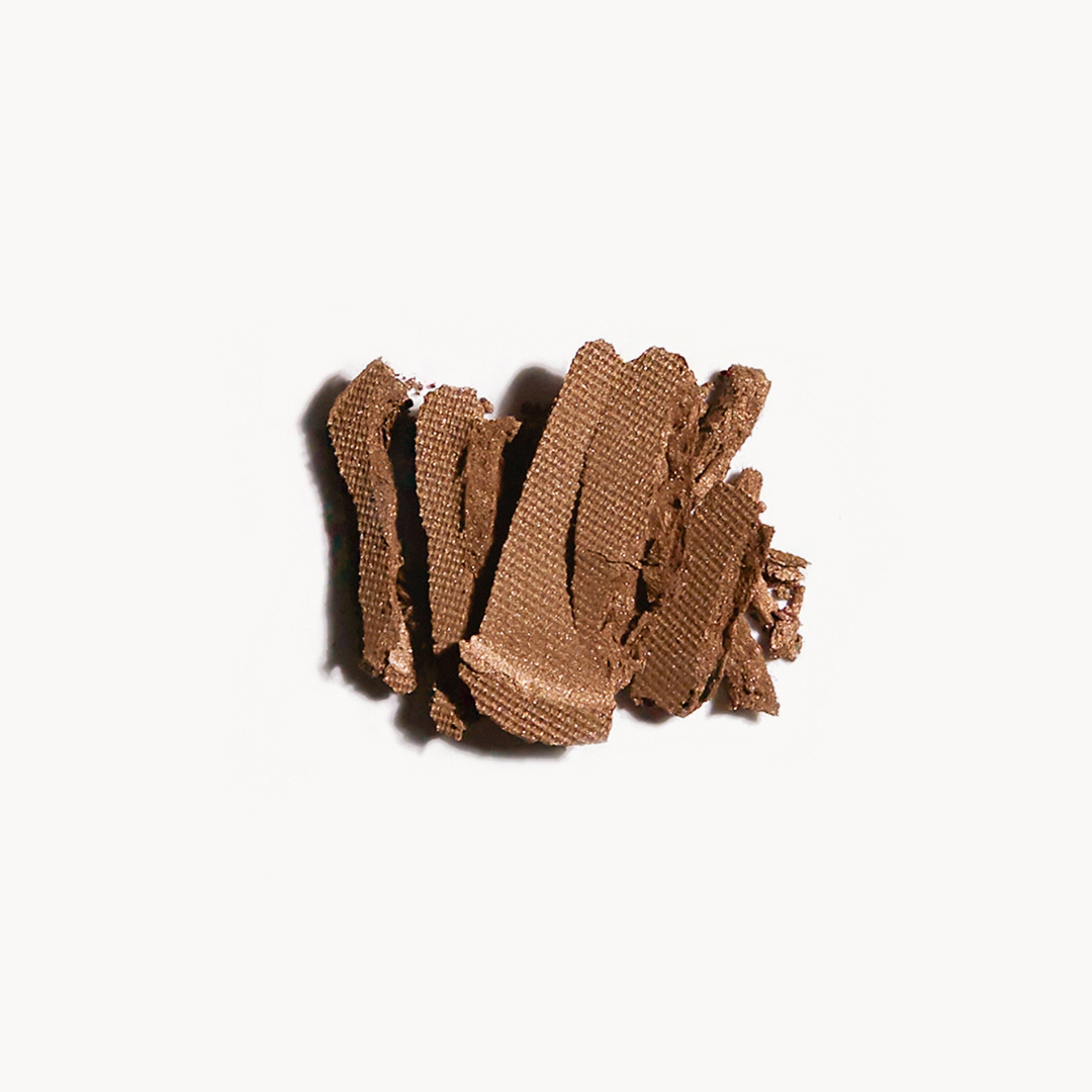 Crumbled up brown-gold eye shadow on a white background
