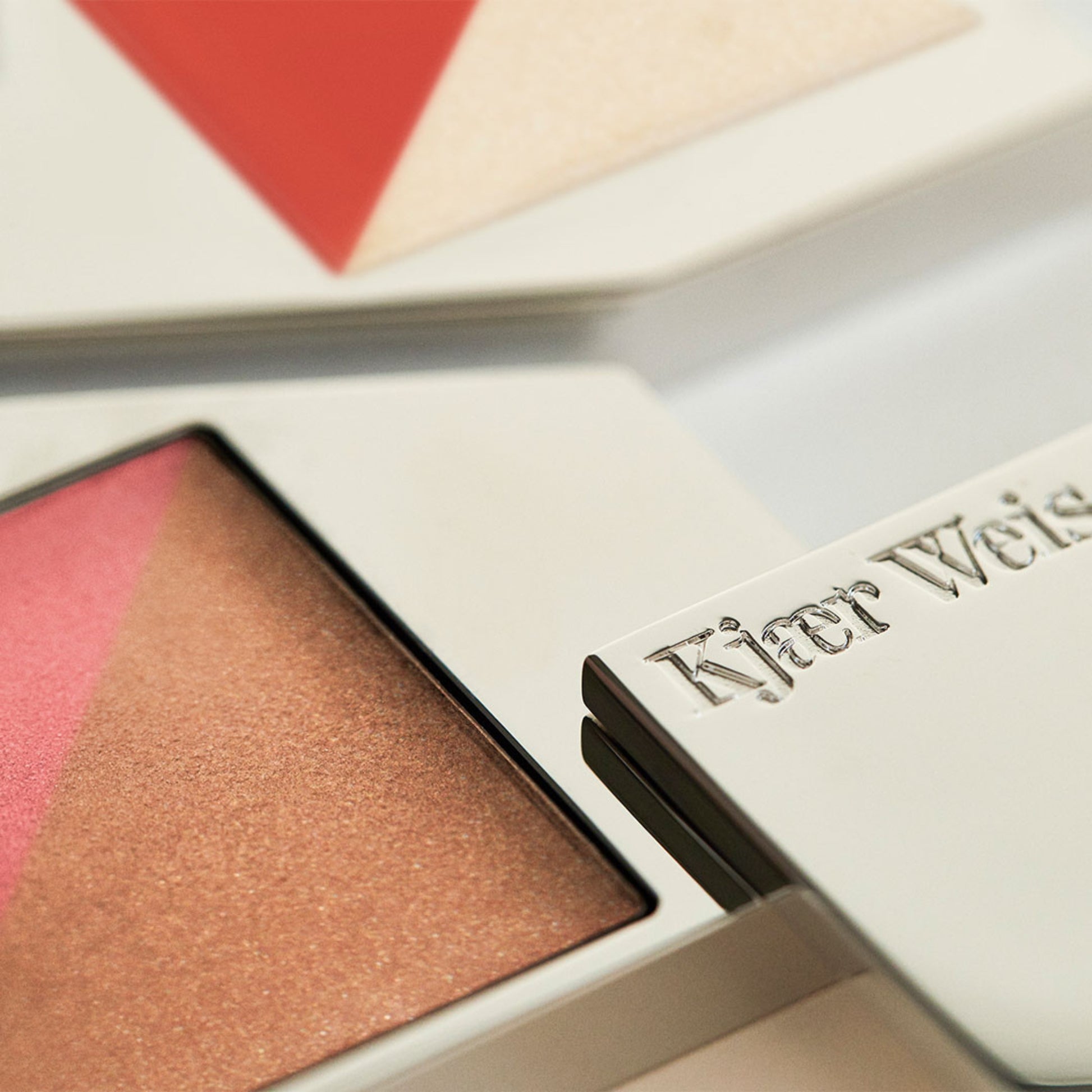 Close up of a flush and glow palette, with Kjaer Weis embossed on the metal packaging