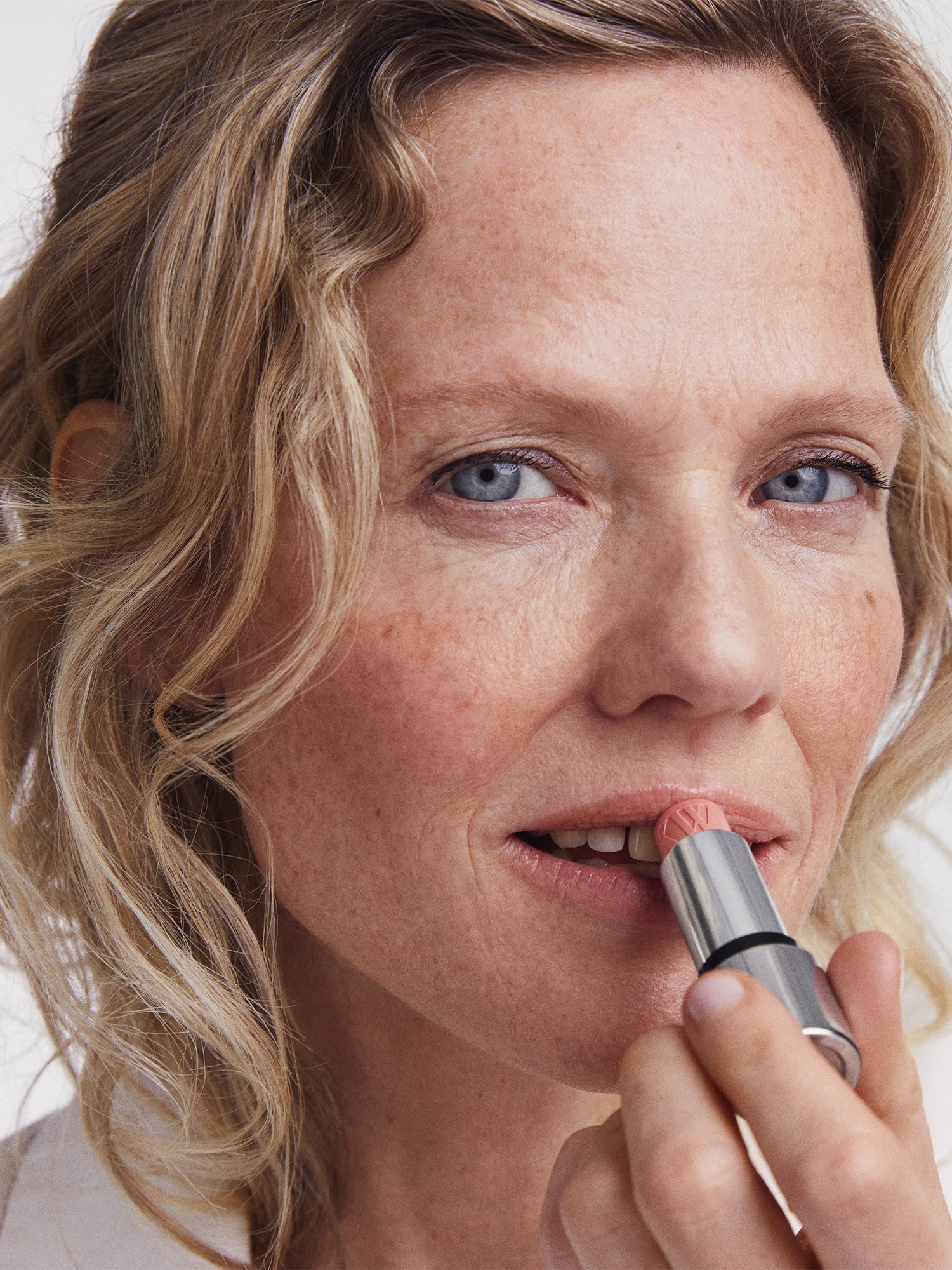 Close-up of a person applying nude Tinted Lip Balm with a neutral background