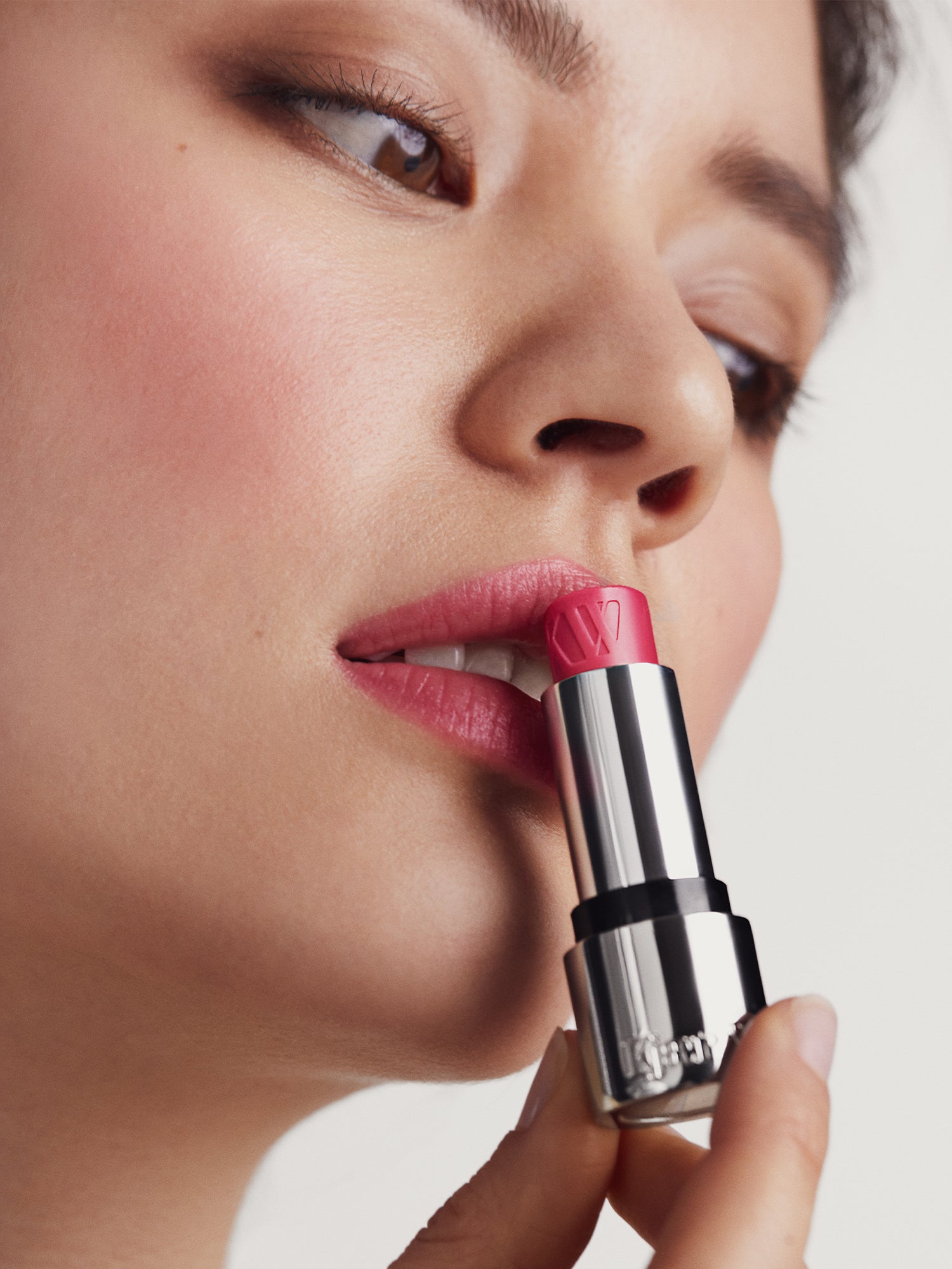 Close-up of a person applying pink Tinted Lip Balm with a neutral background