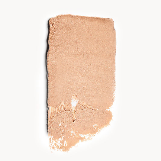 a wipe of fair, neutral-toned cream foundation on a white background