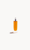 Glass bottle with white pipette top and gold-coloured liquid inside on a white background