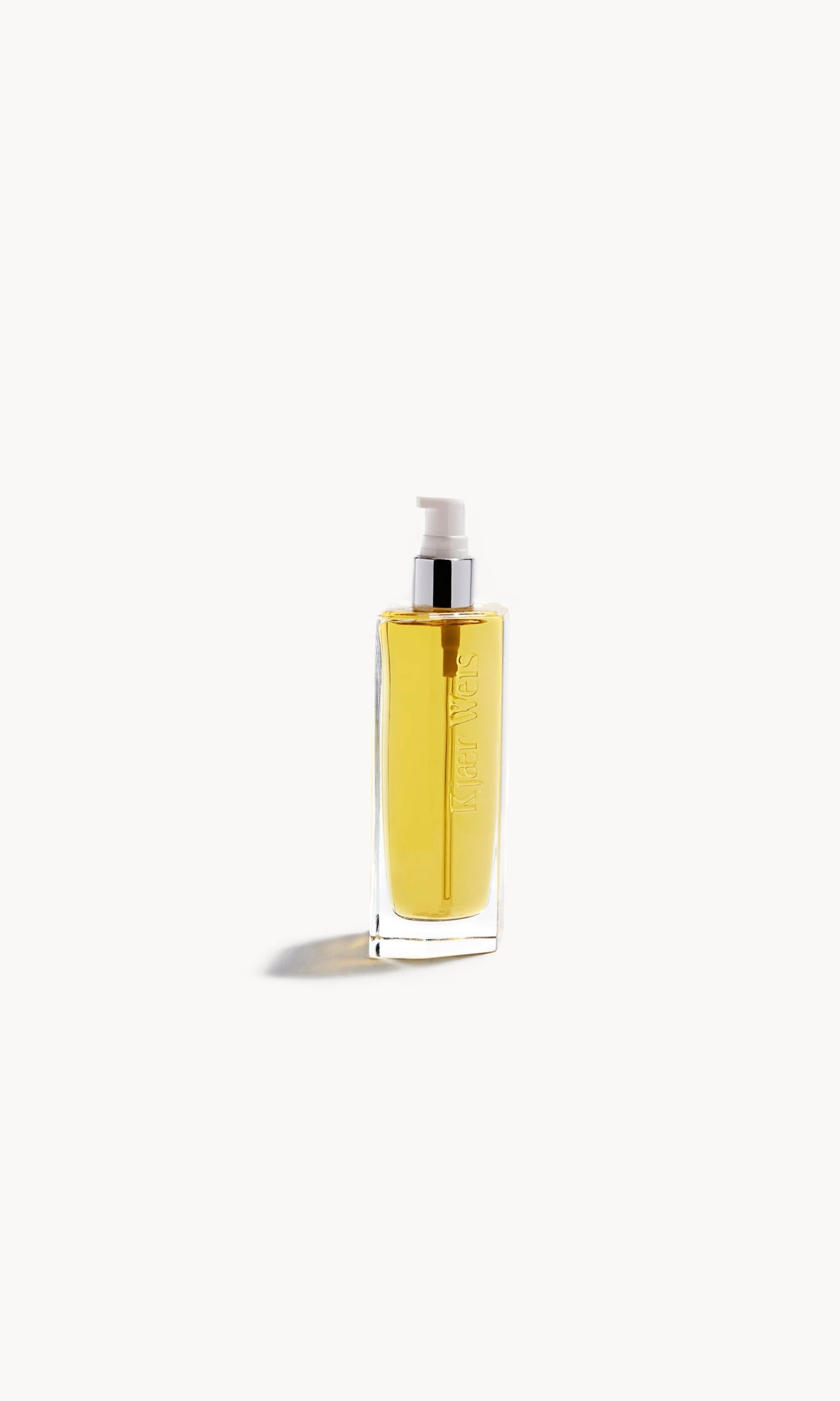 Kjaer Weis body oil in glass bottle with cap removed, showing a white pump