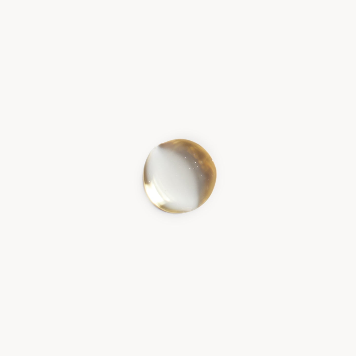 A droplet of Kjaer Weis body oil on white background