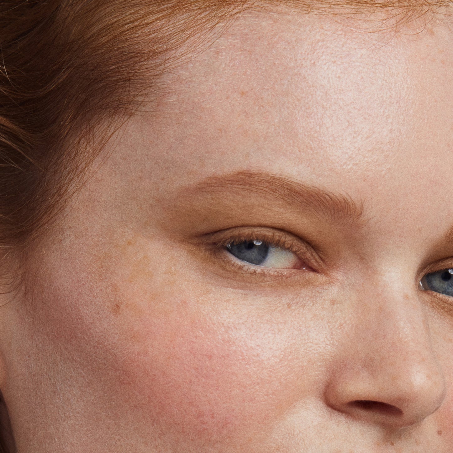 Close up of a person’s face with a fair skin tone wearing cream blush 