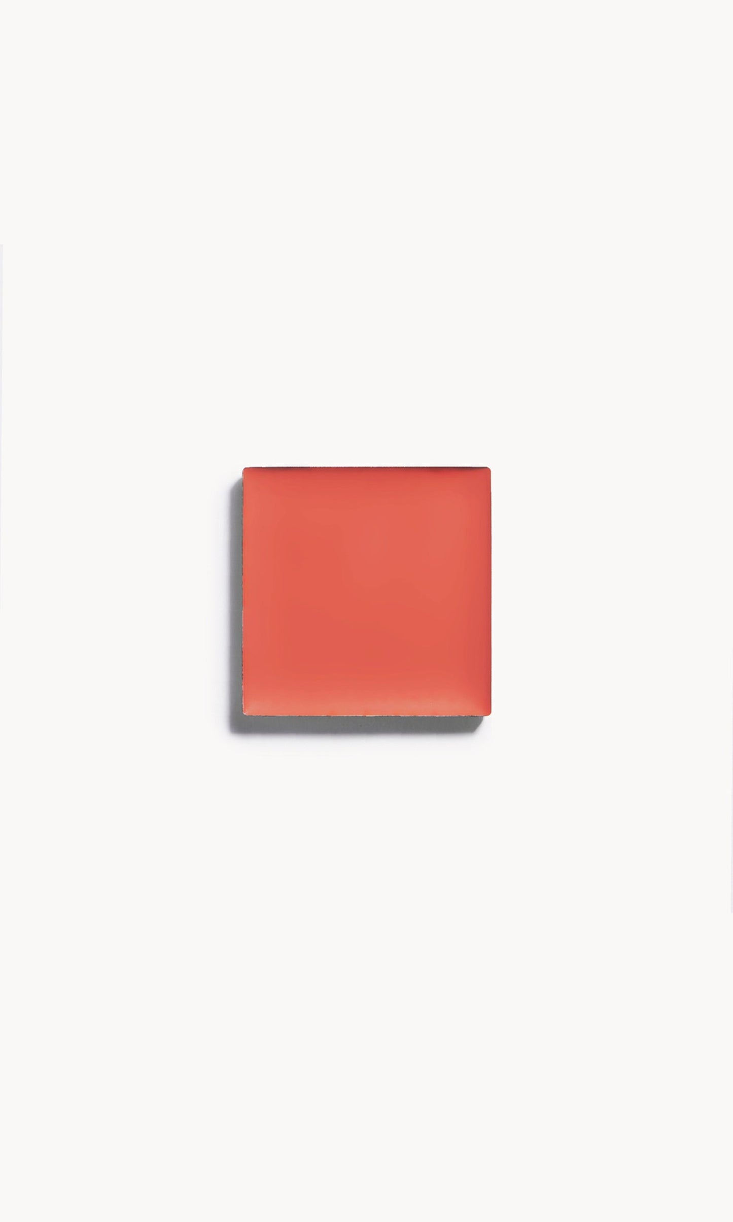 A square of warm coral cream blush on a white background