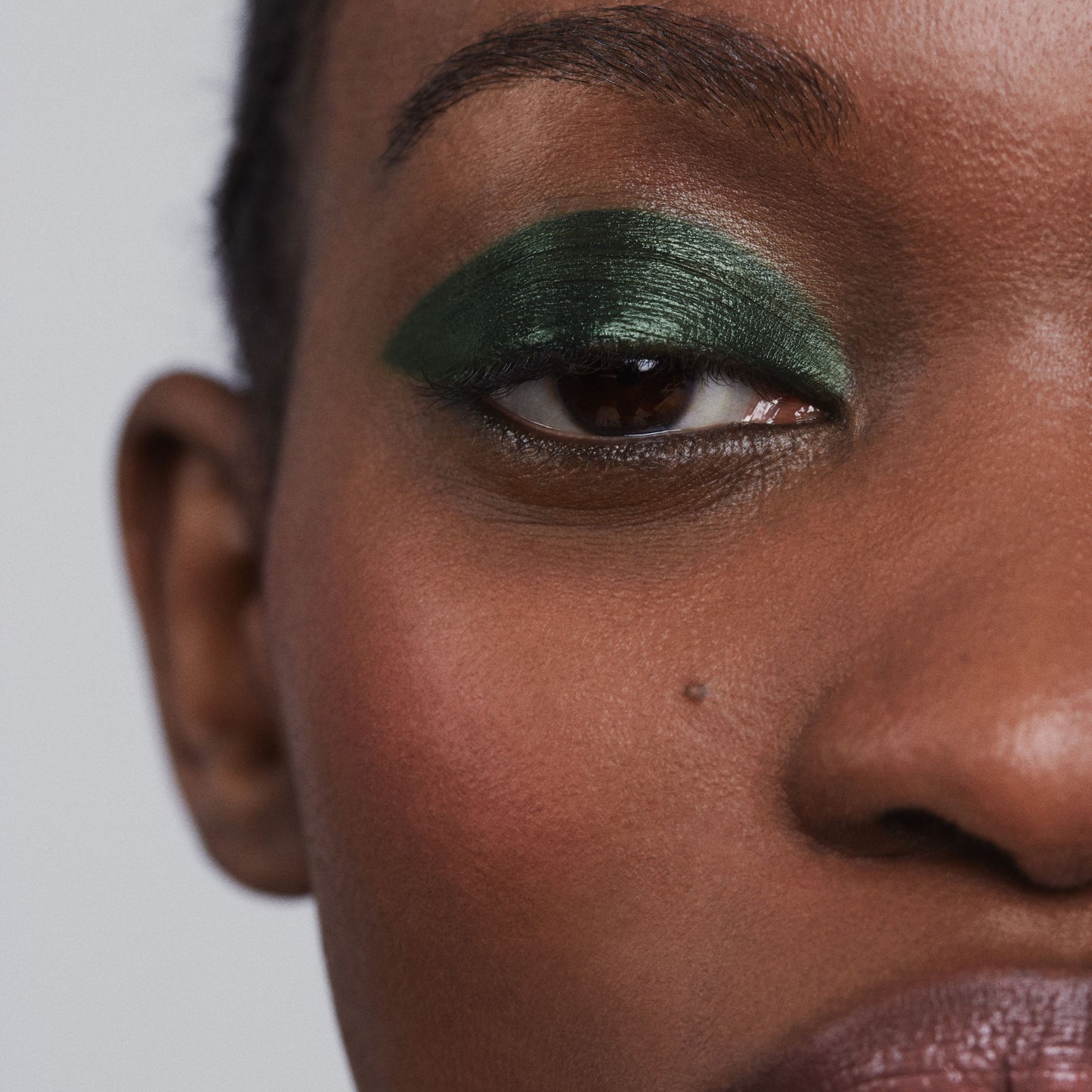 Close up of person’s eye with a deep skin tone wearing cream eye shadow