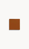 Square of deep neutral cream foundation on a white background