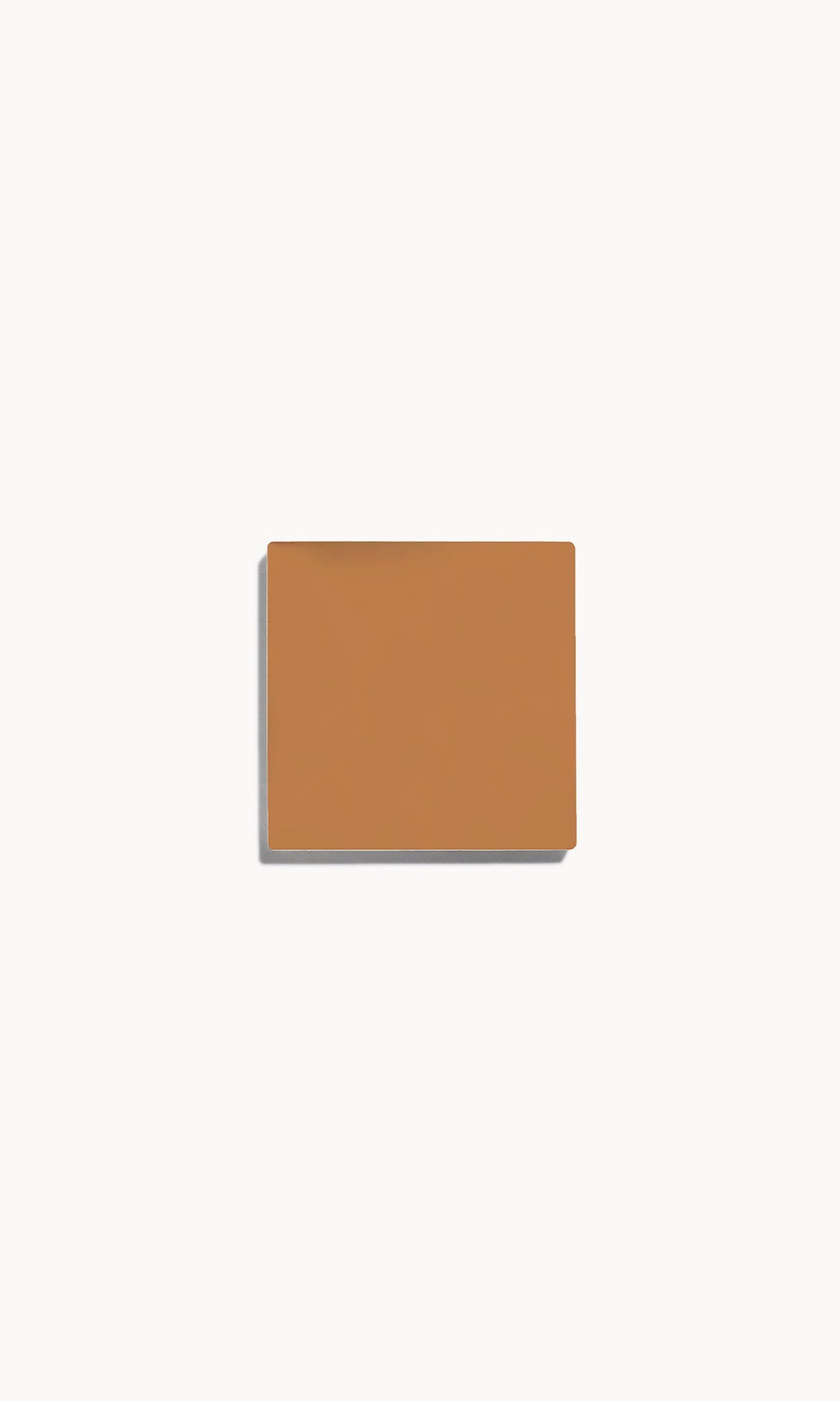 Square of warm tan cream foundation on a white background