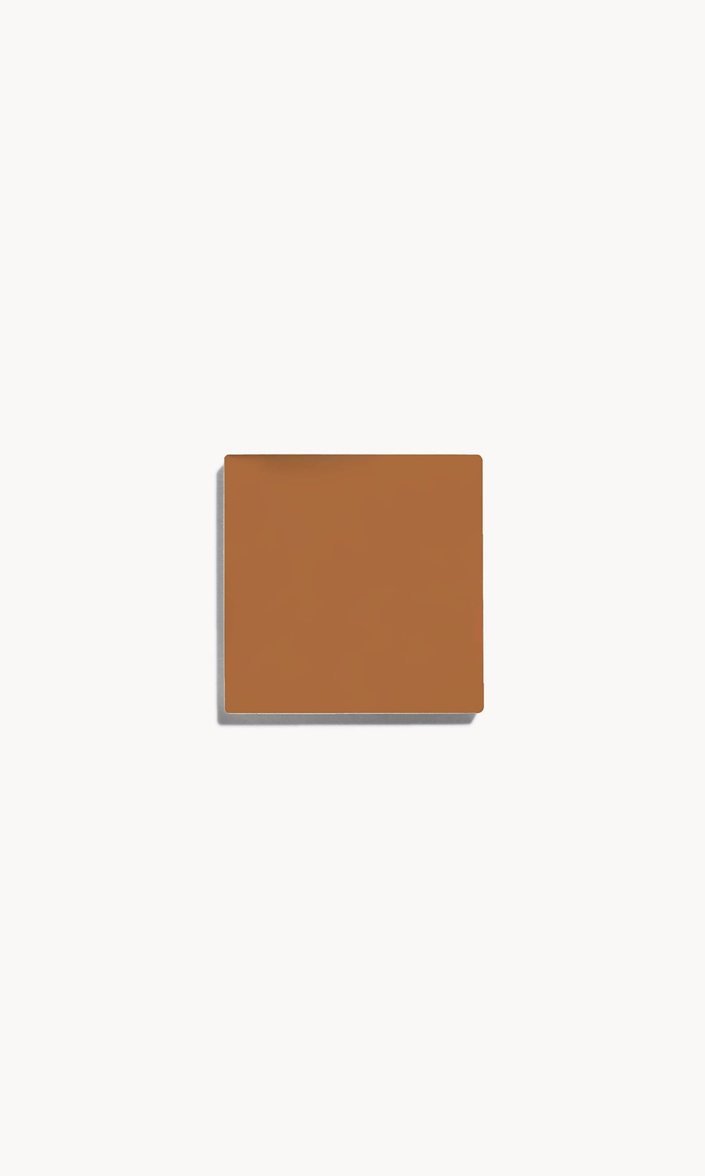 Square of warm tan cream foundation on a white background