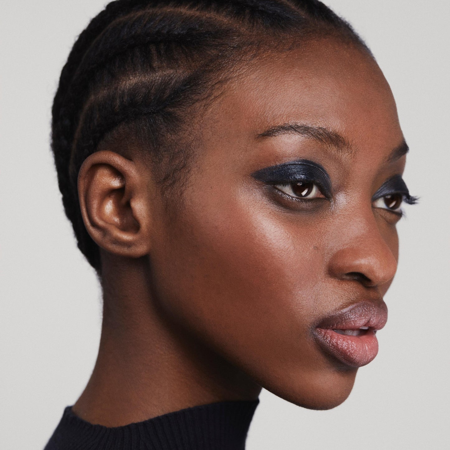 Close up of person’s face with a deep skin tone wearing cream eye shadow