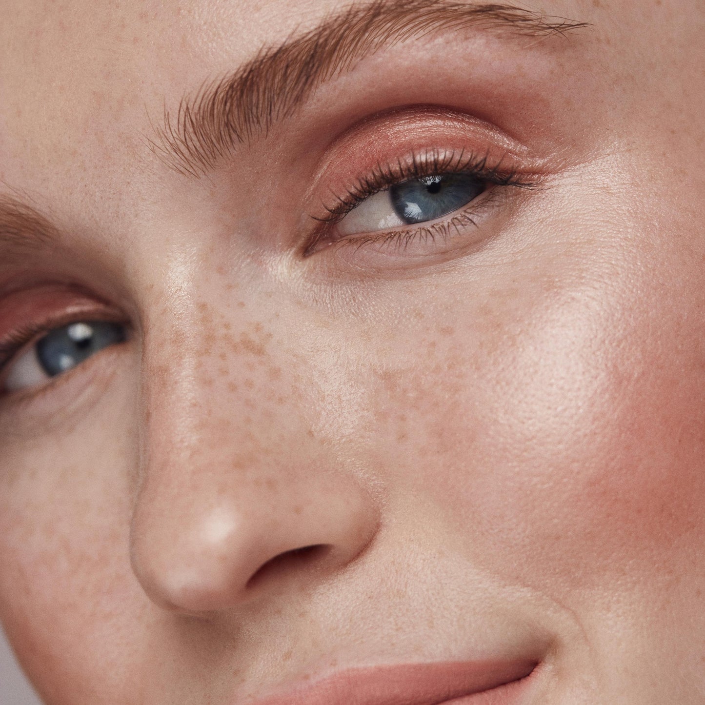 Close up of a person’s face with a fair skin tone wearing cream highlighter