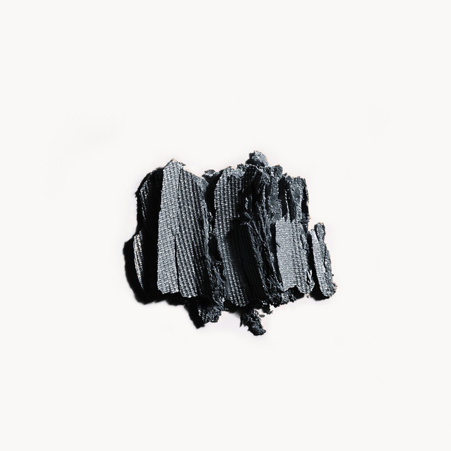 Crumbled up dark grey eye shadow on a white background