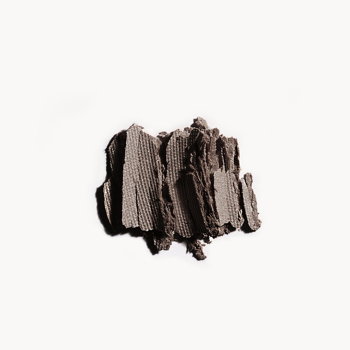 Crumbled up greyish brown eye shadow on a white background