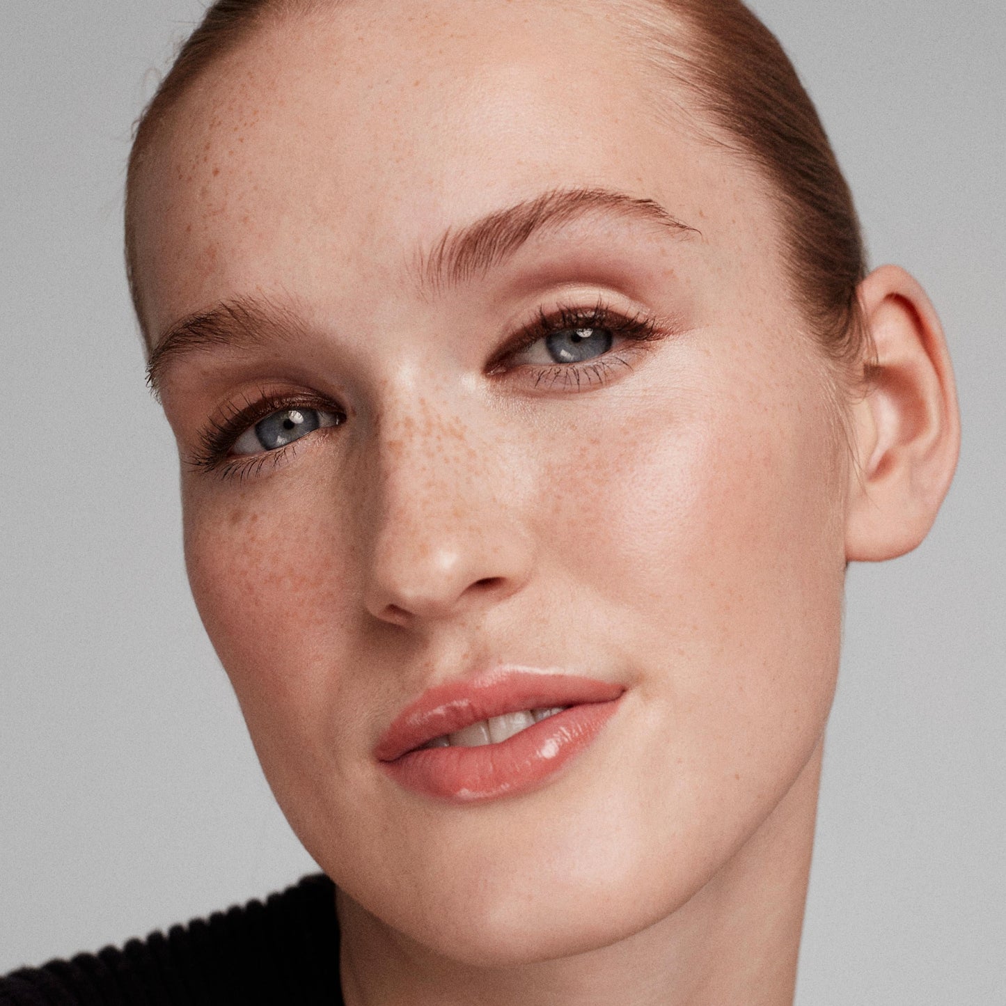 Close up of a person’s face wearing earthy brown eyeliner on the top lash line 