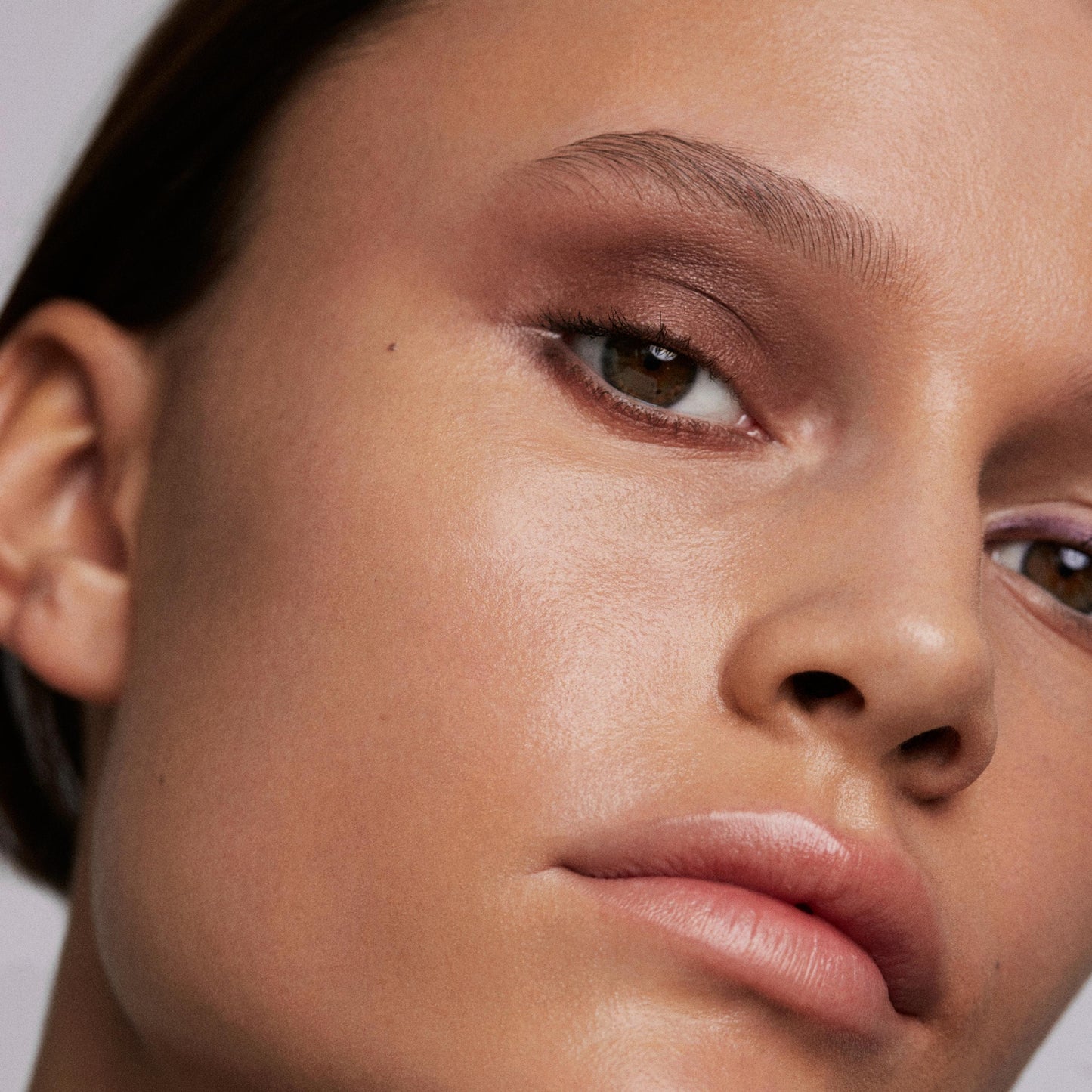 Close up of a person’s face wearing metallic reddish-brown eye shadow