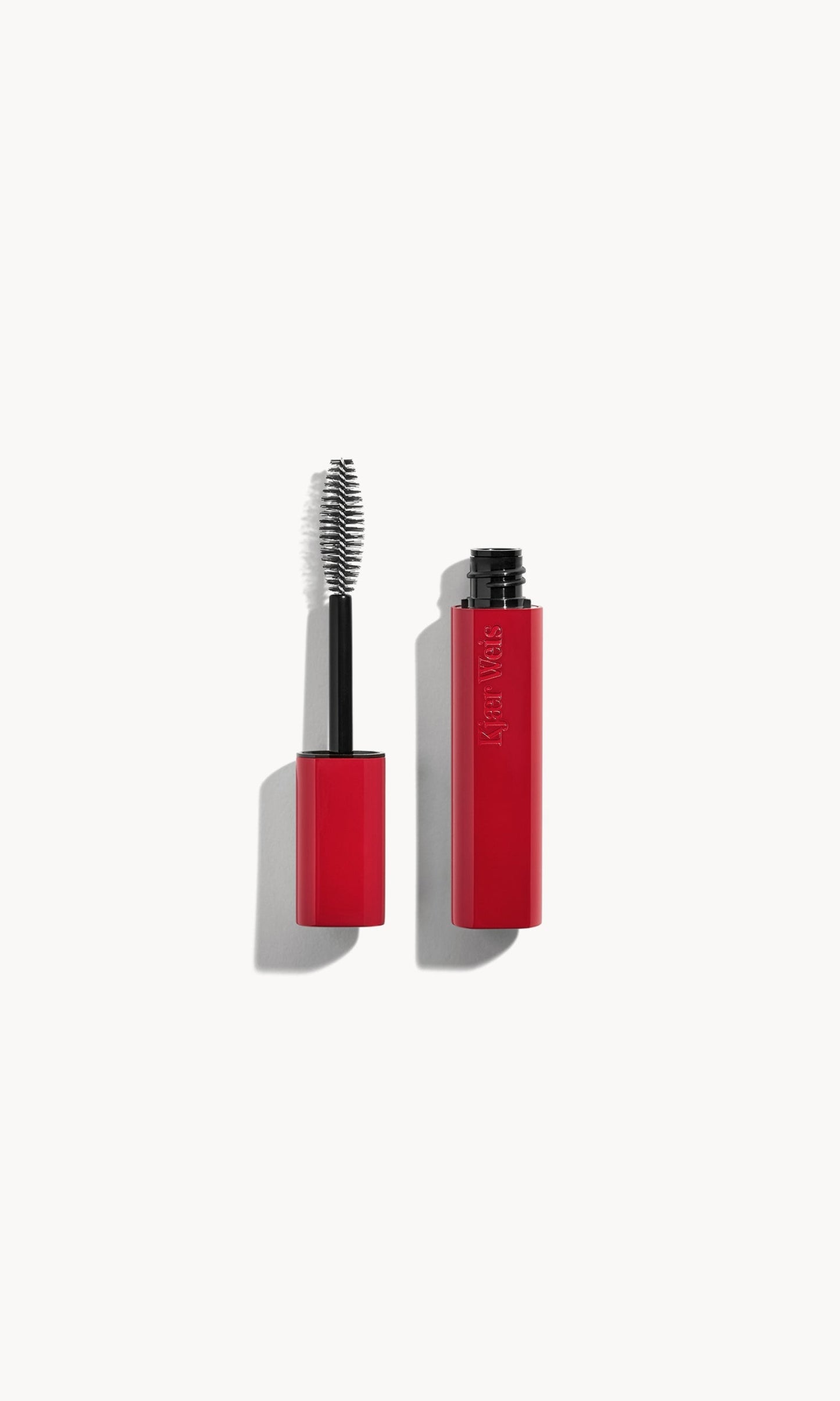 A red tube of mascara next to the mascara wand with a red lid