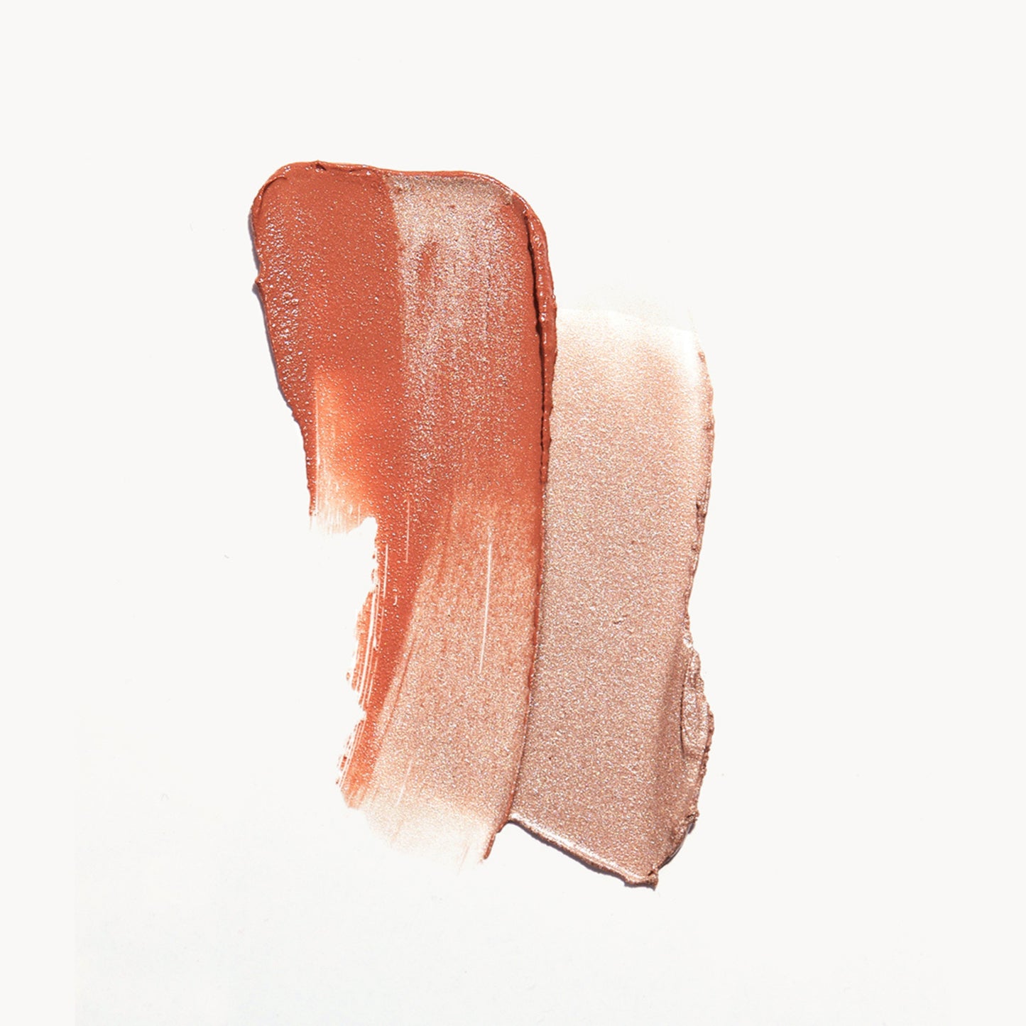 A wipe of bronze-coloured cream blush and a sheer nude cream highlighter on a white background