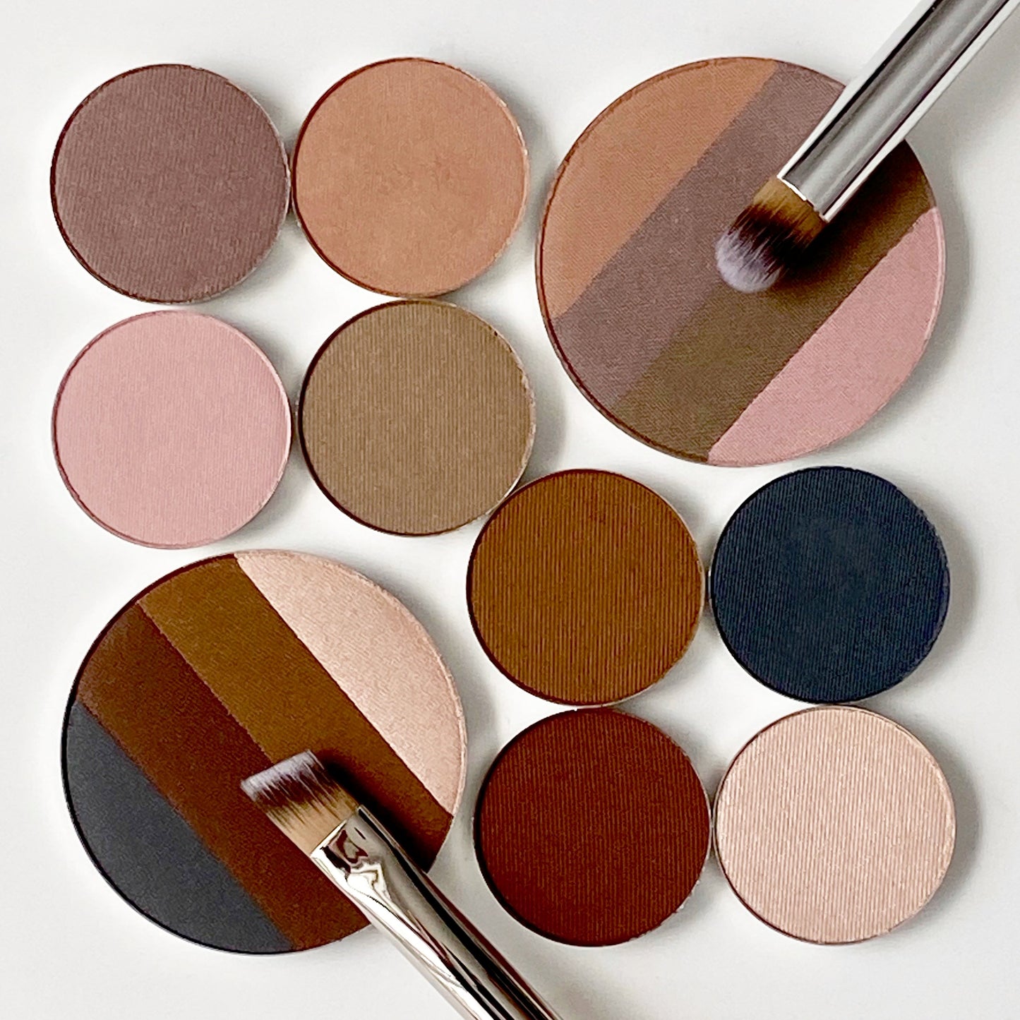 Eye shadow palette refills arranged with the large quadrant eye shadow next to the four smaller refills of each shade.