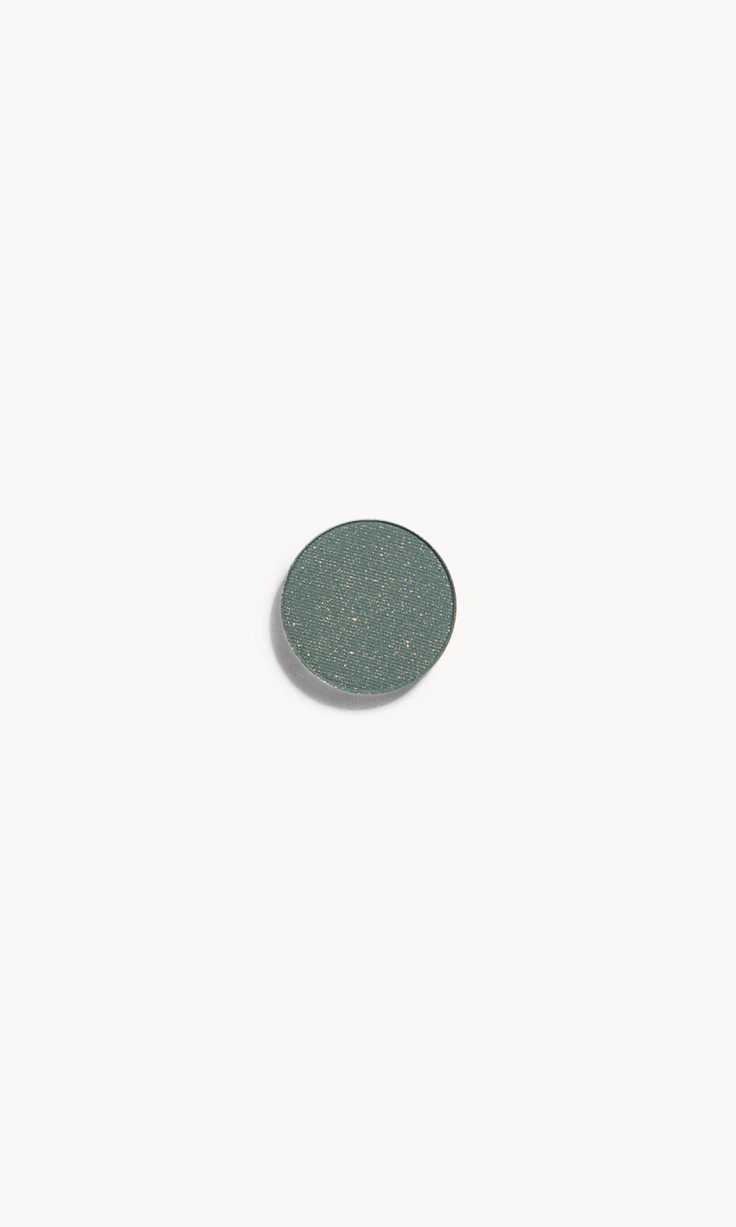 A circle of green eye shadow with gold flecks on a white background