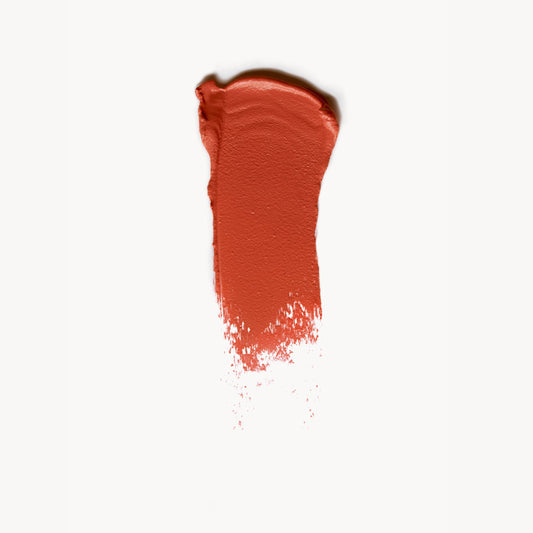a wipe of warm coral cream blush on a white background