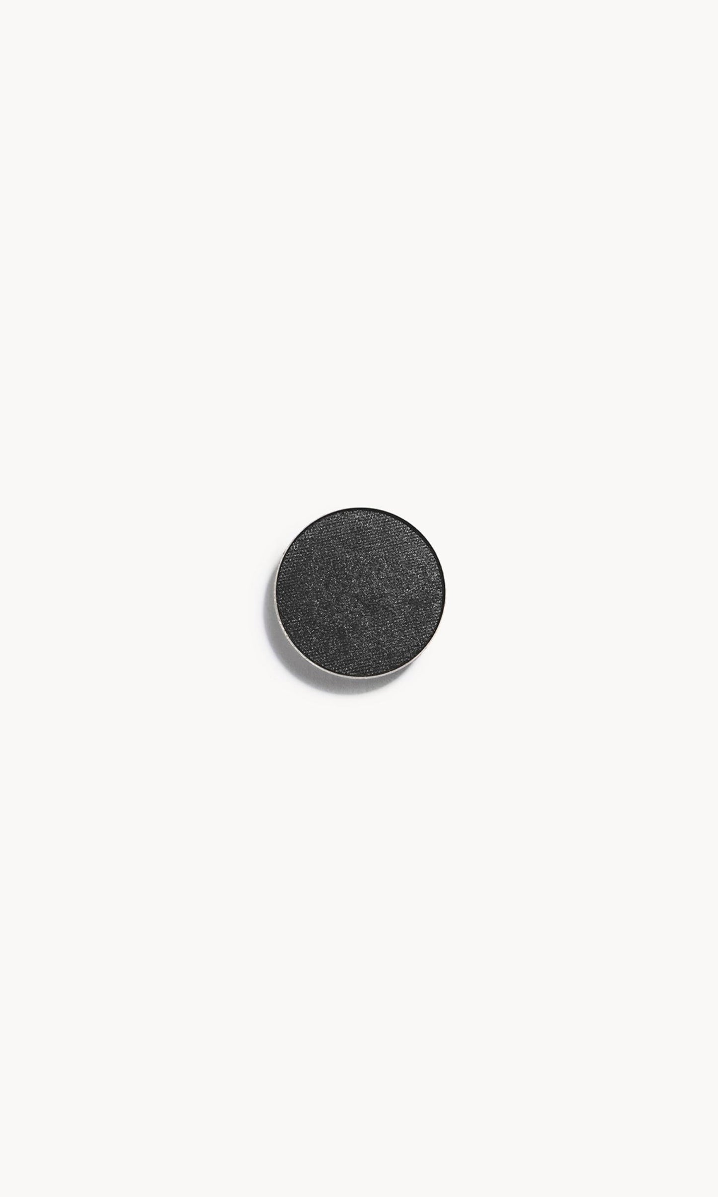 A circle of black eye shadow with silver shimmer on a white background