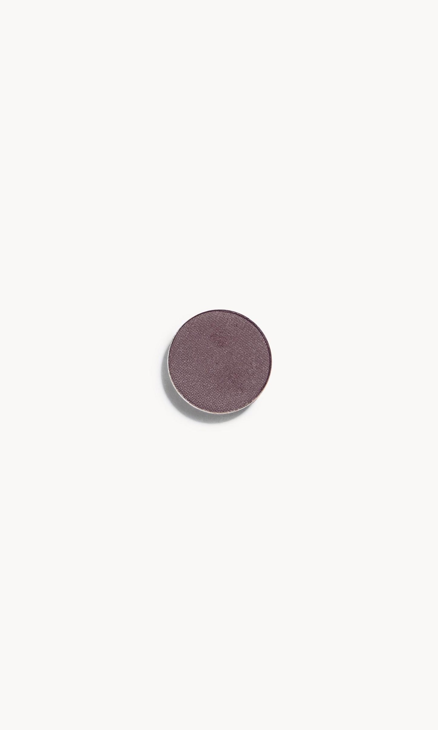 A circle of greyish purple eye shadow on a white background