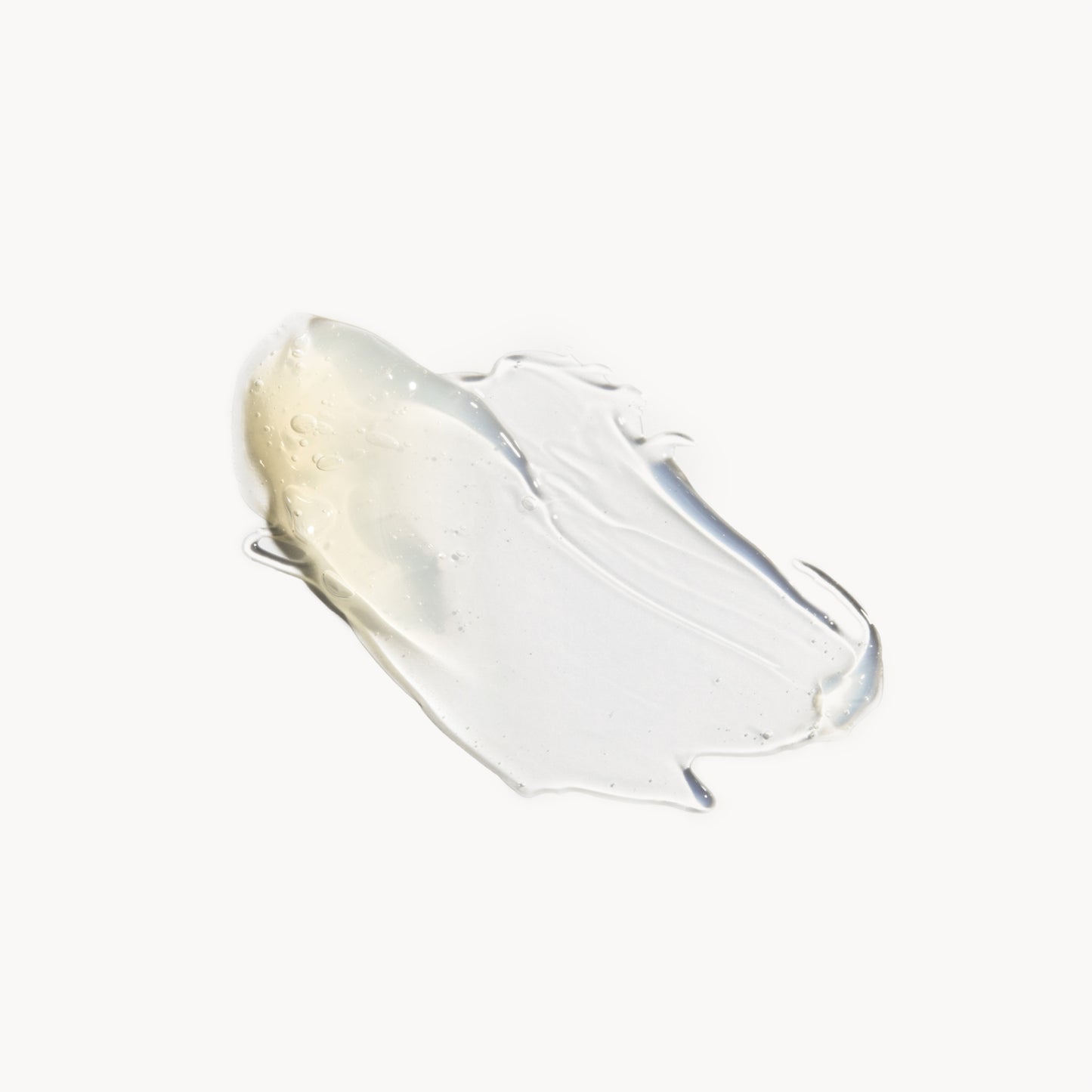 A deposit of cleanser on a white background. The product is gold-coloured, turning clear when it is thinned out.