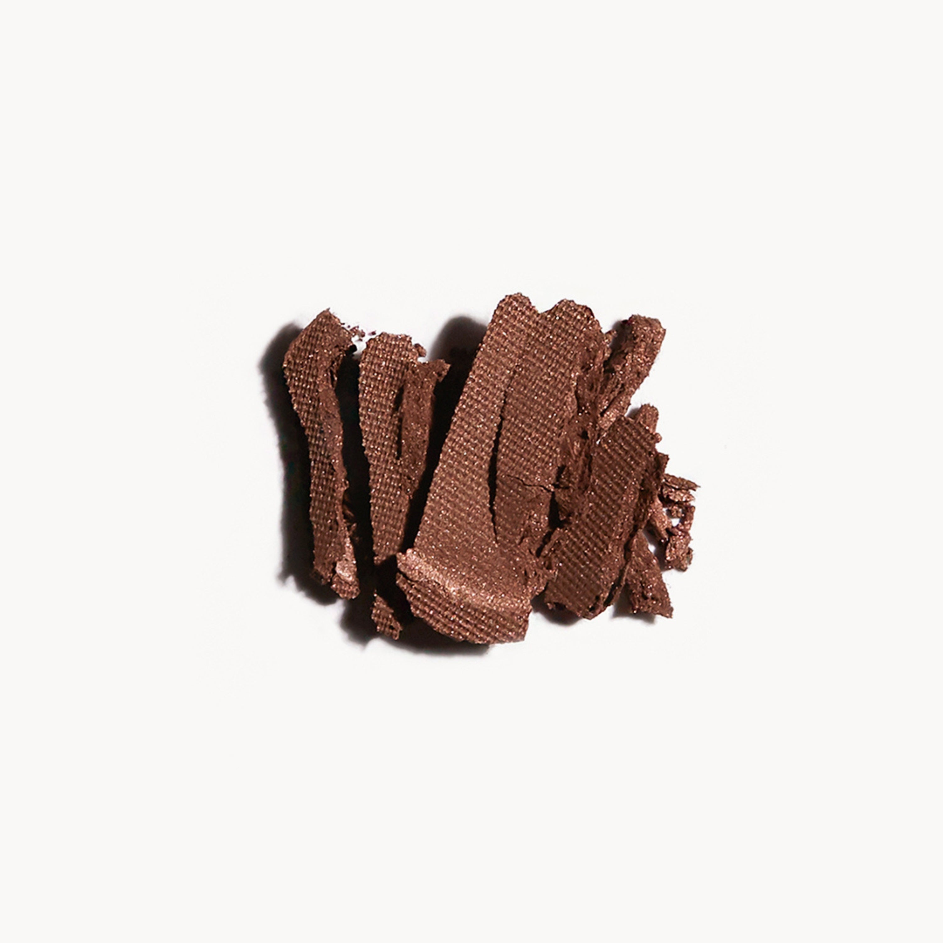 Crumbled up warm brown eye shadow on a white background