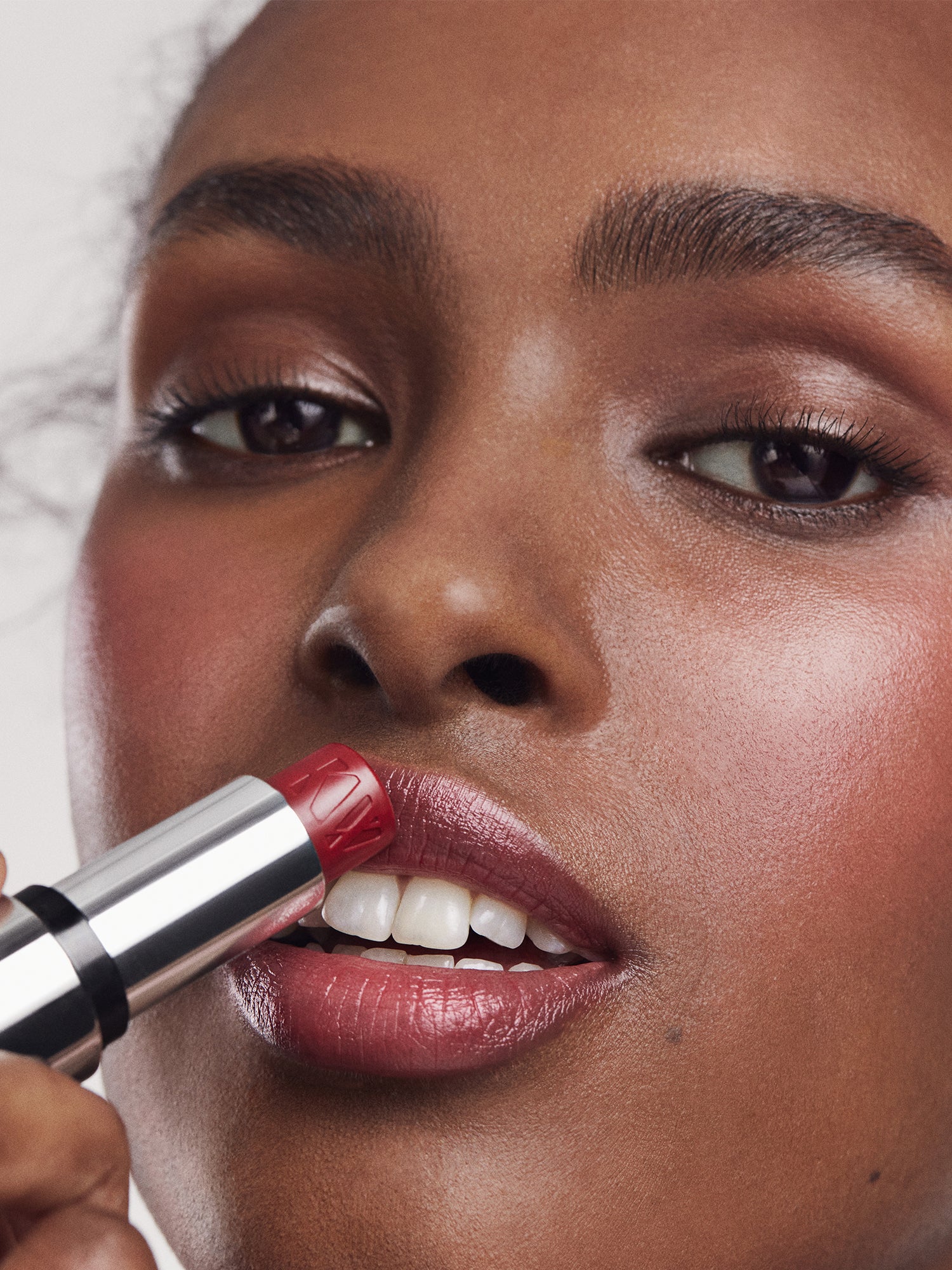 Close-up of a person applying red Tinted Lip Balm with a neutral background