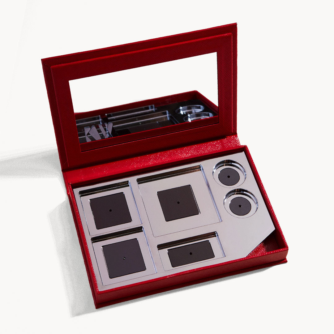 An open kit box with six empty palette sections and mirror on the inside of the lid