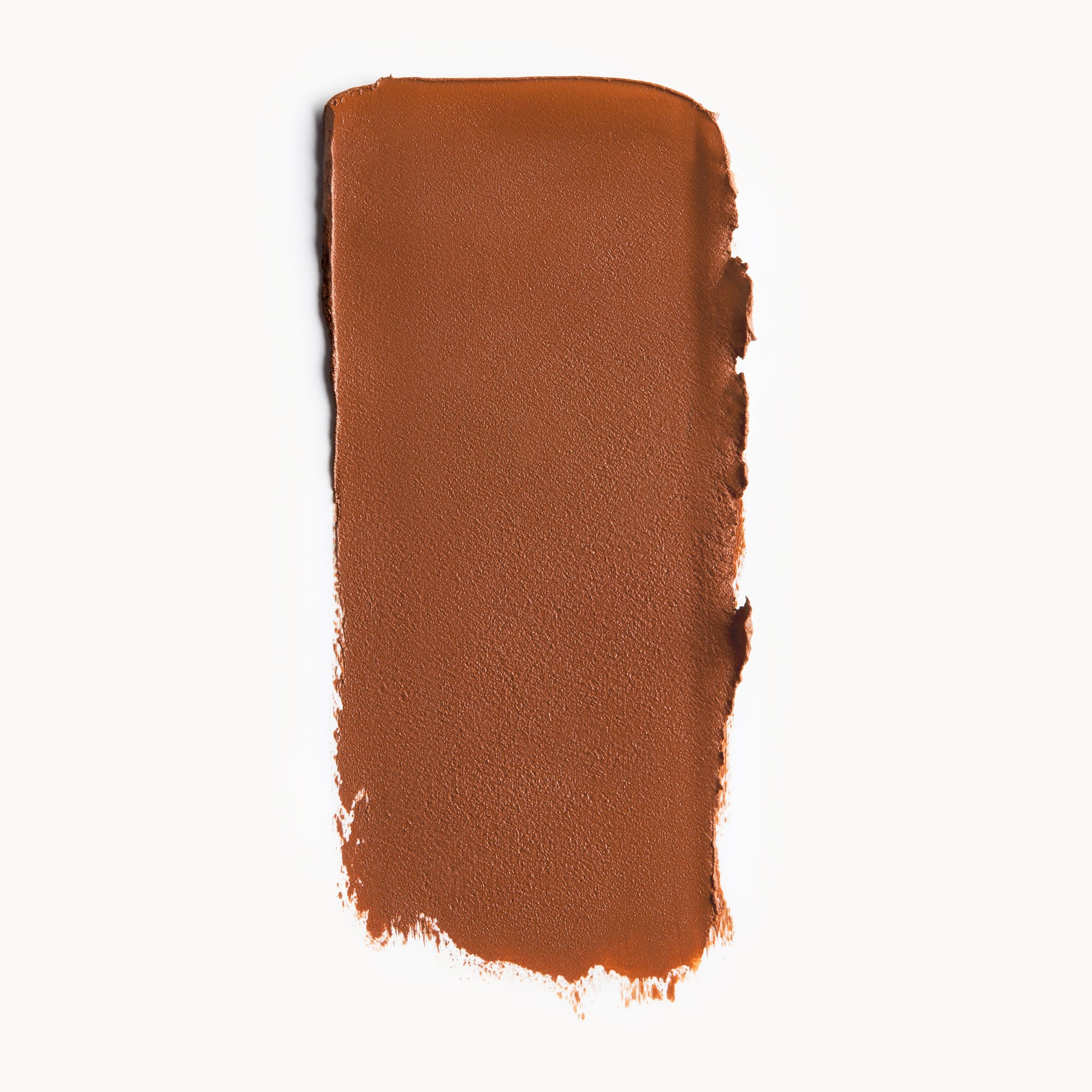 A wipe of deep, neutral-toned cream foundation on a white background  