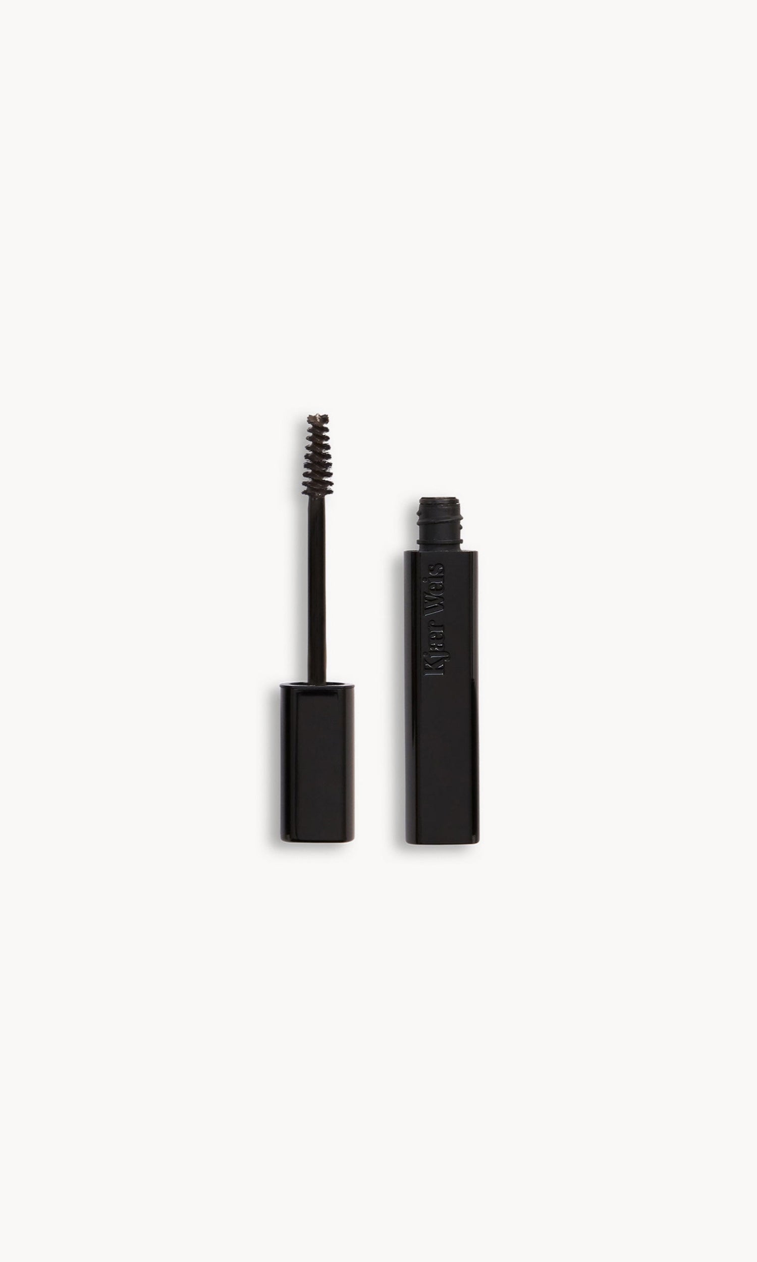 Black Kjaer Weis brow gel wand and bottle side by side, with dark brown product on the wand