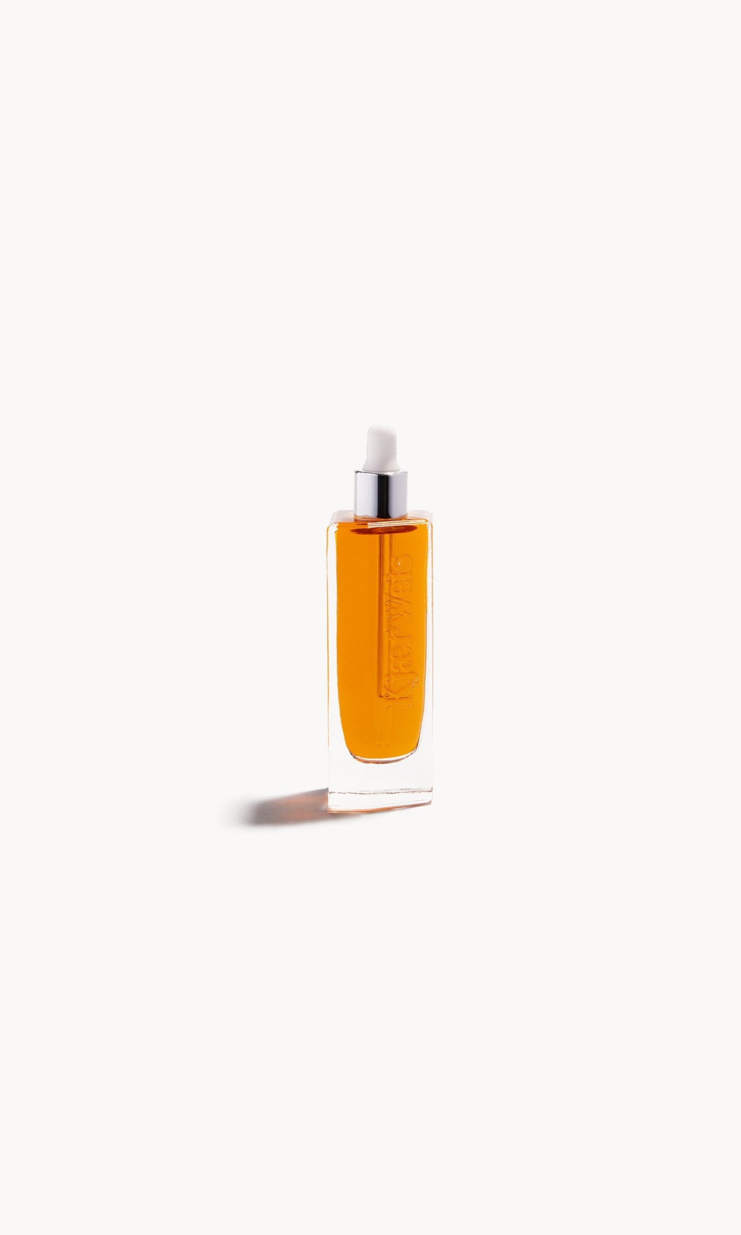 glass bottle with white pipette top and gold-coloured liquid inside on a white background