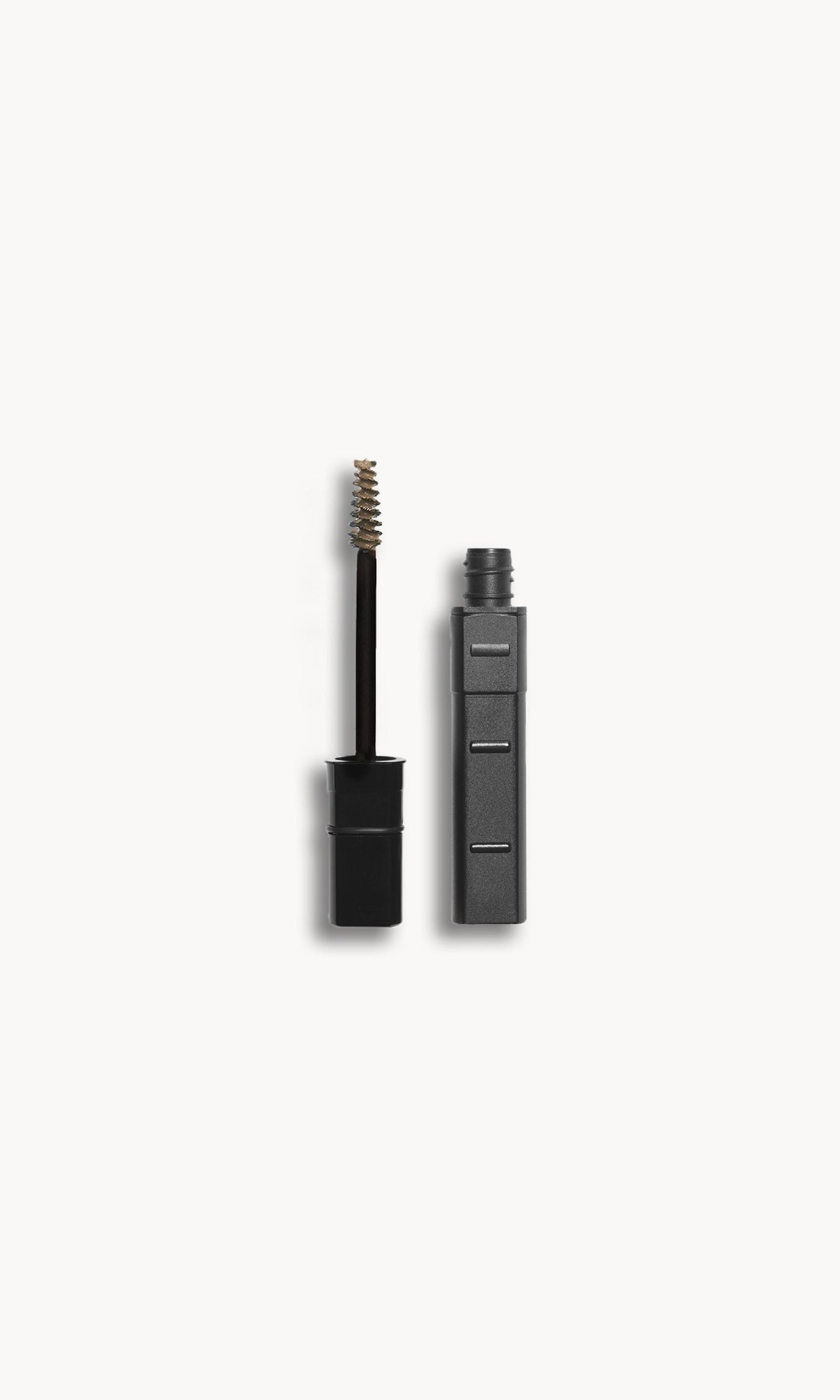 Kjaer Weis brow gel refill case next to a wand with blonde product on it