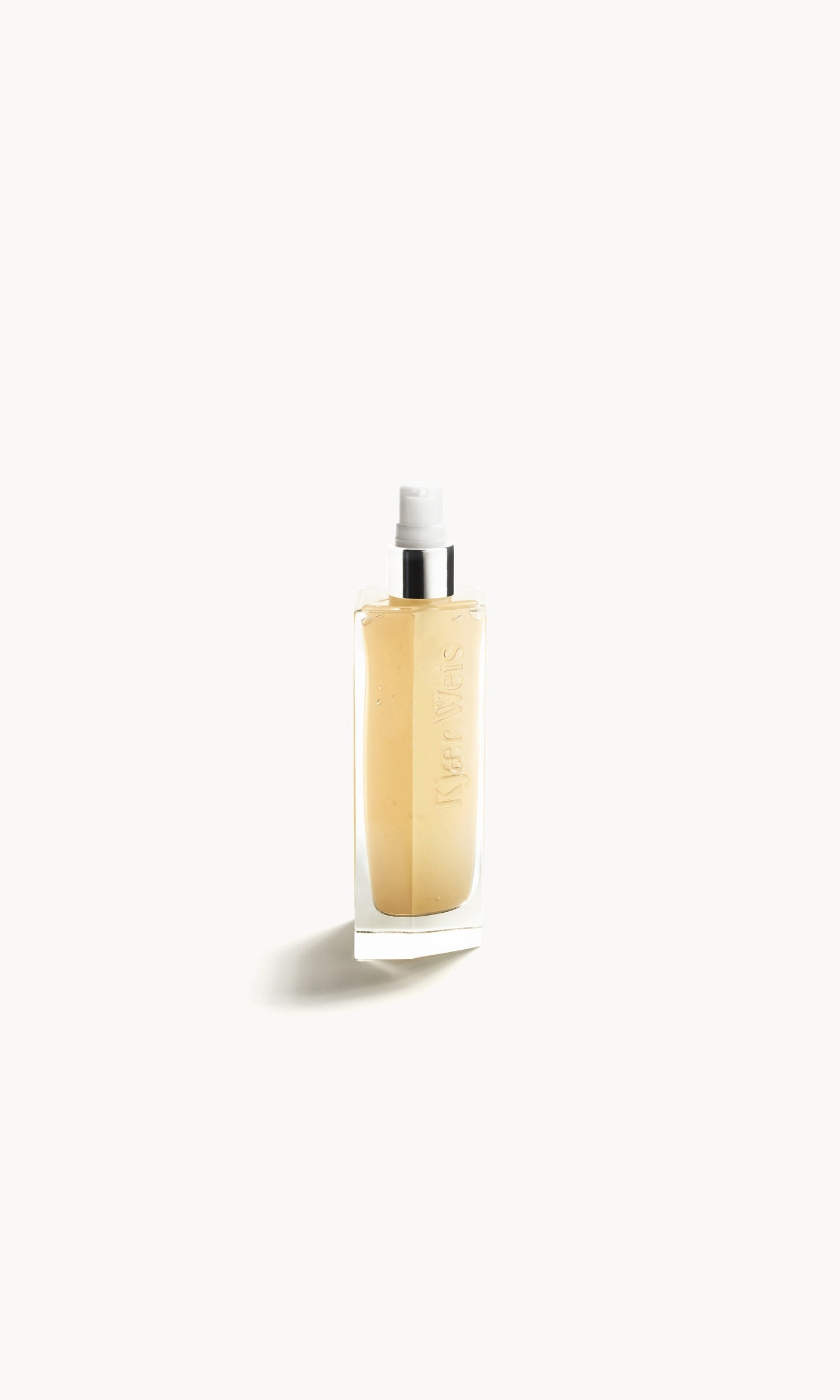 Kjaer Weis cleanser in a clear bottle with the lid removed, showing a white and silver pump