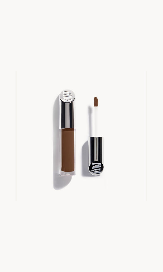 kjaer weis concealer in a clear bottle with silver metal top next to the concealer wand