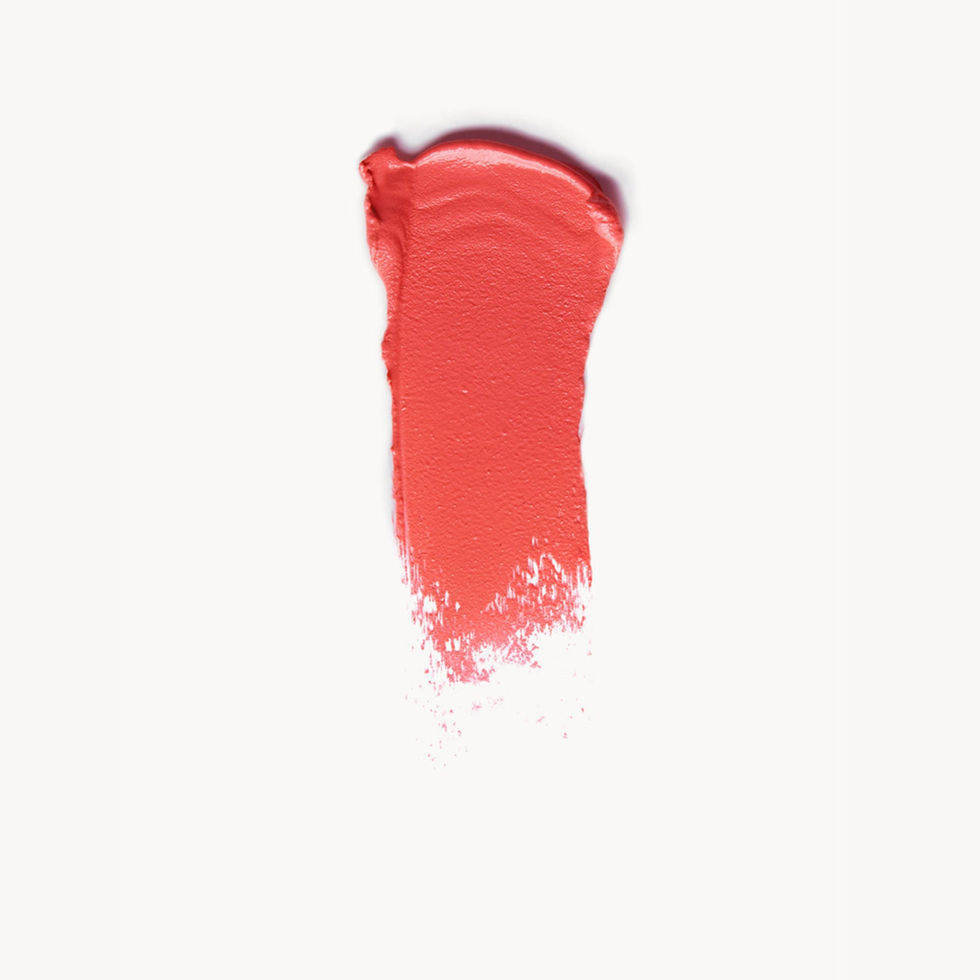 A wipe of bright coral cream blush on a white background