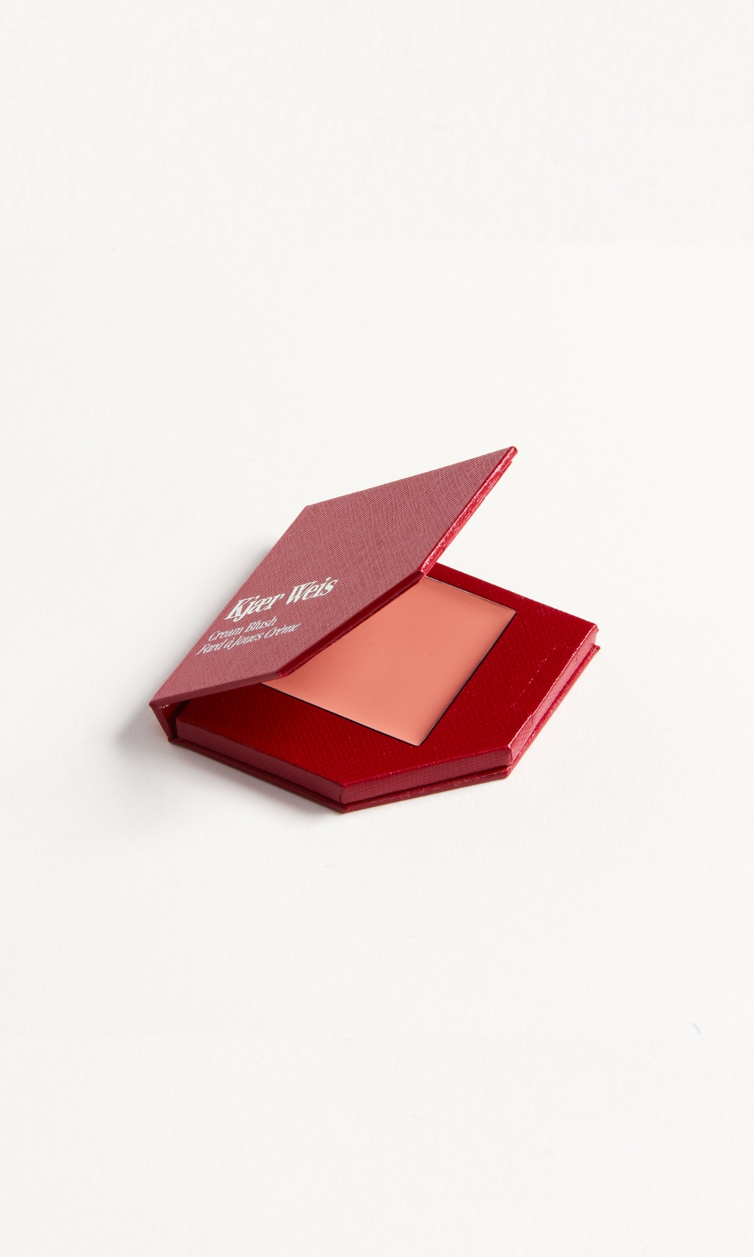A red KW palette with the lid open to show the cream blush