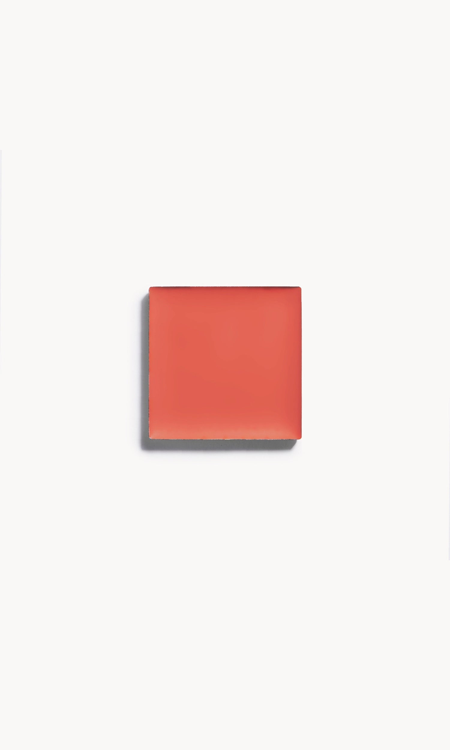 a square of warm coral cream blush on a white background