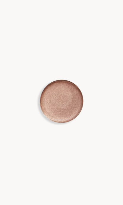 Circle of iridescent light mocha-coloured cream eye shadow on white background