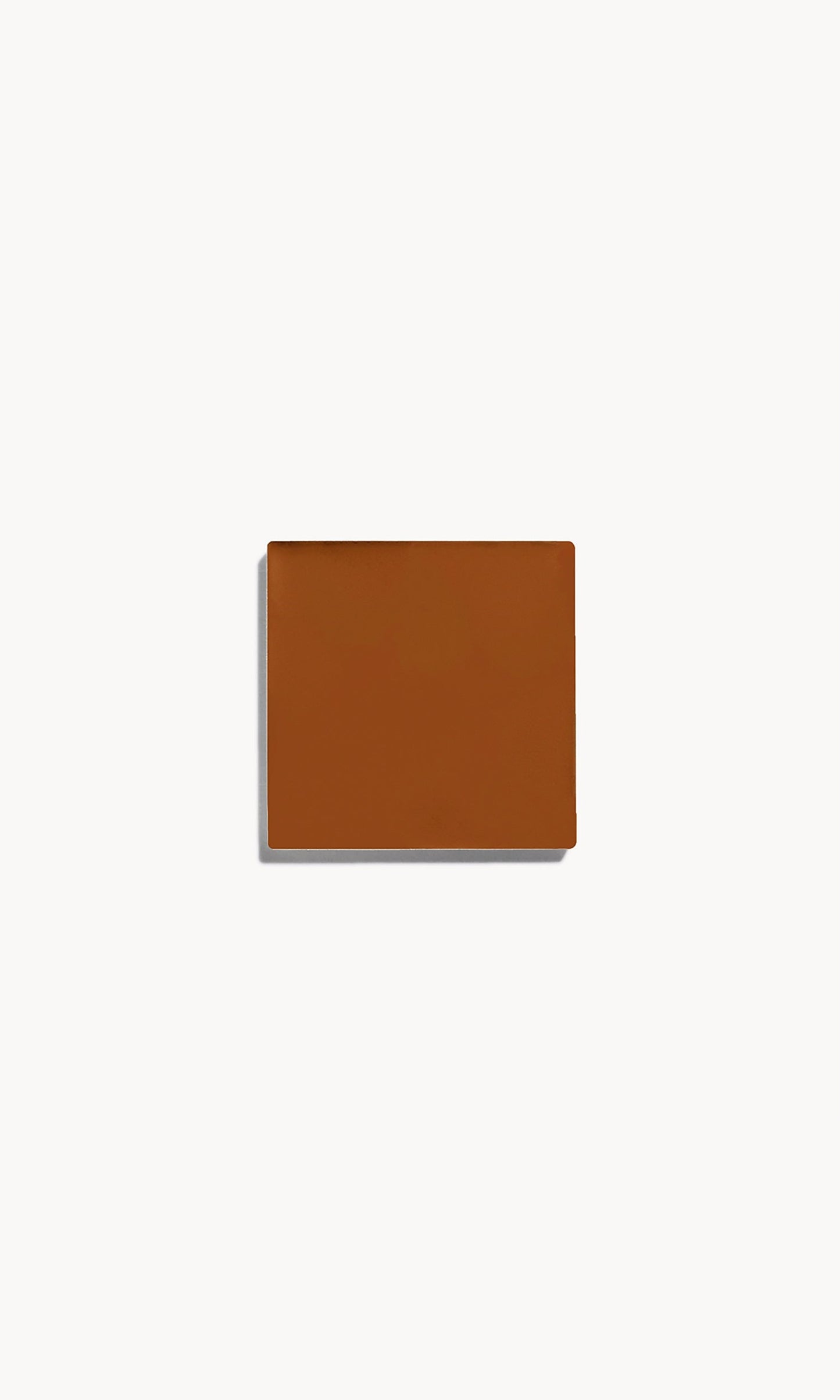 Square of deep neutral cream foundation on a white background