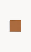 Square of warm tan cream foundation on a white background