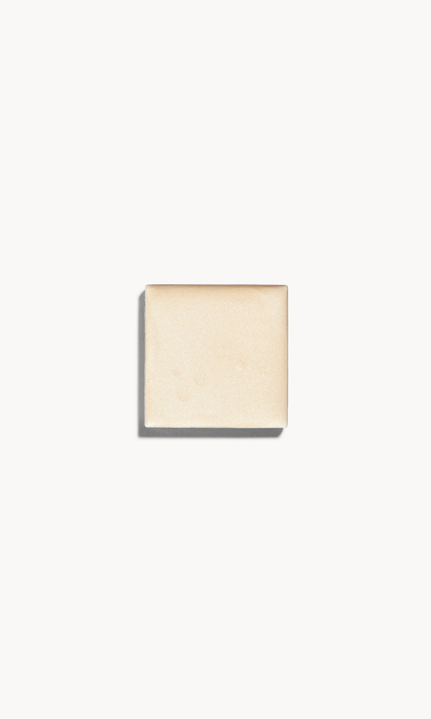 A square of warm golden champagne cream highlighter on a white background