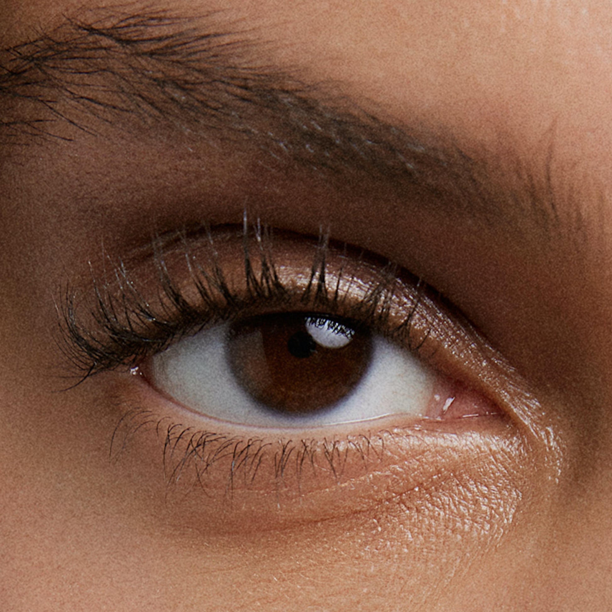close up of person’s eye with a medium skin tone wearing cream eye shadow