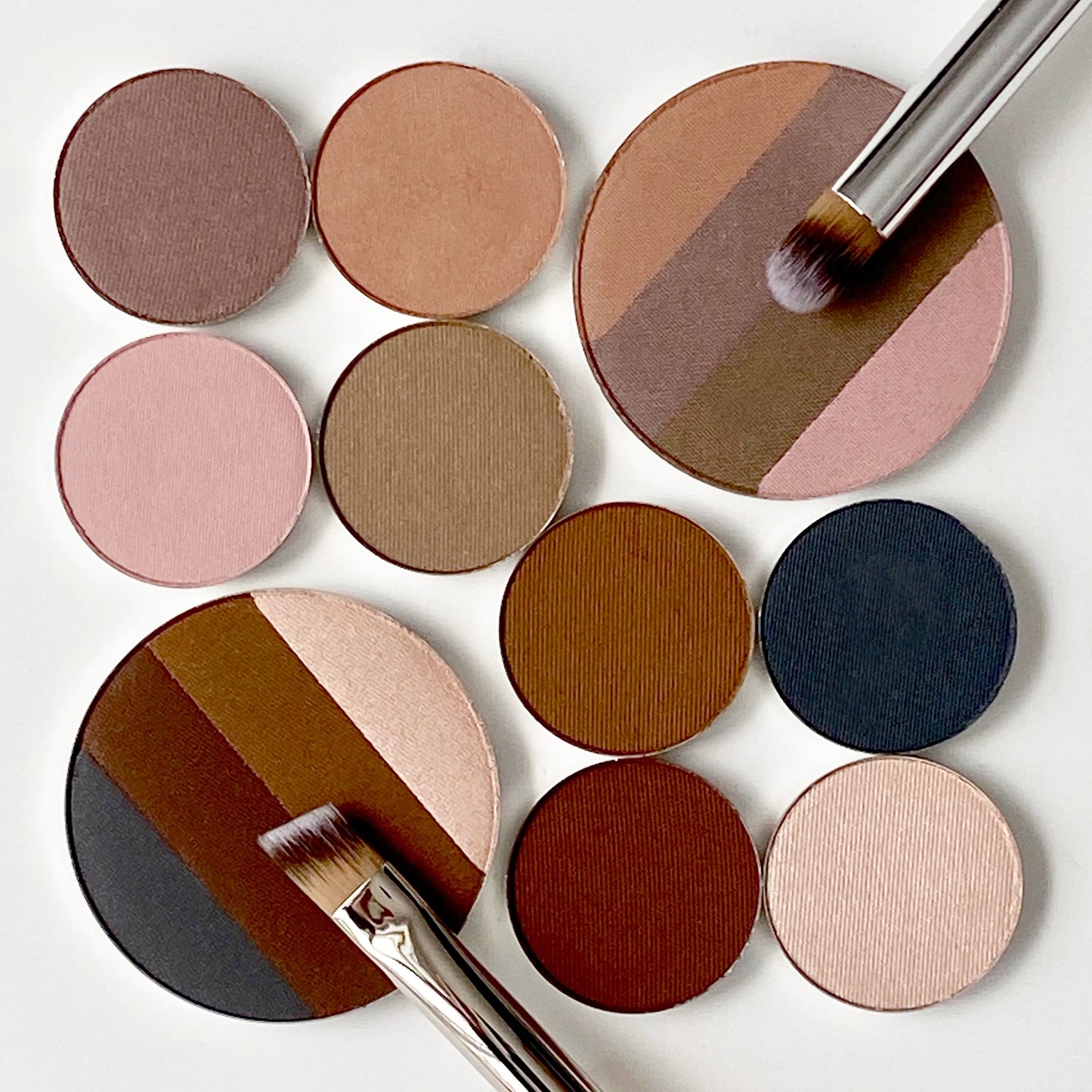Eye shadow palette refills arranged with the large quadrant eye shadow next to the four smaller refills of each shade. 