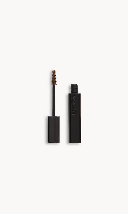Black Kjaer Weis brow gel wand and bottle side by side, with a very light brown product on the wand