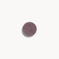 A circle of greyish purple eye shadow on a white background