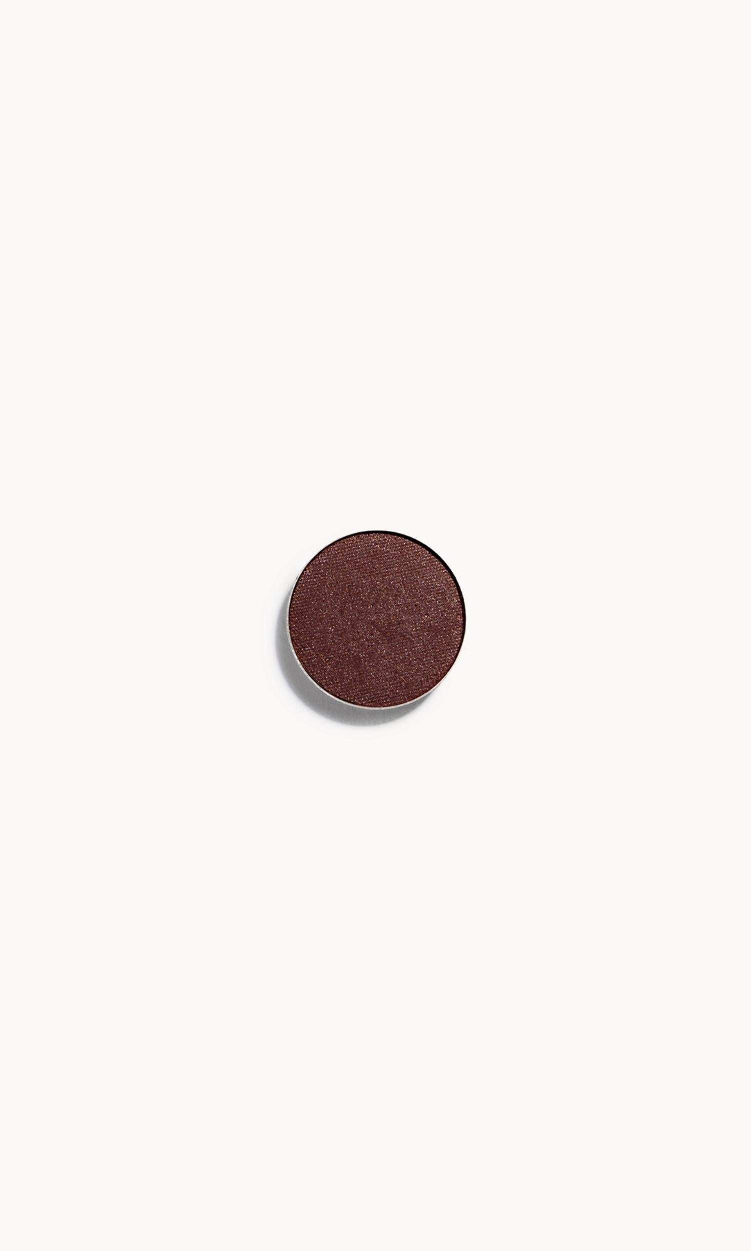 a circle of metallic reddish-brown copper eye shadow on a white background
